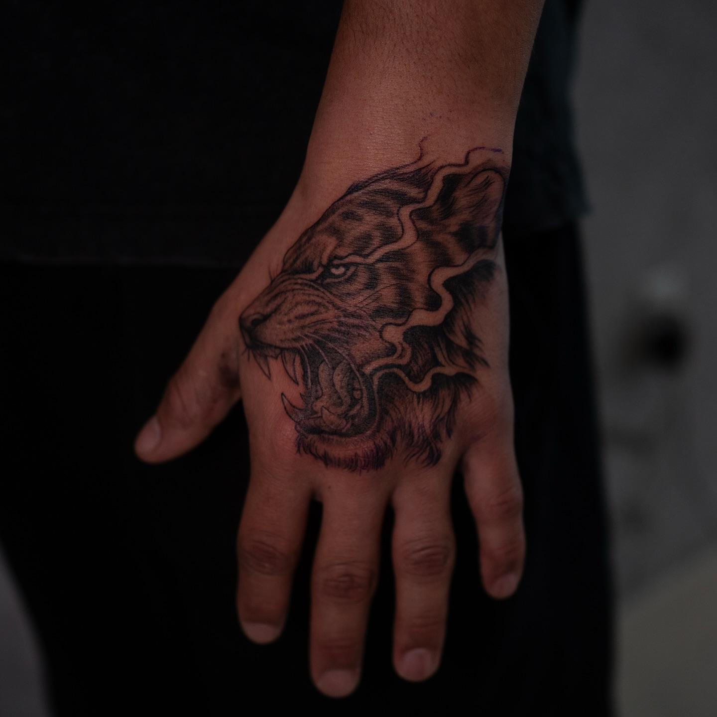 Lion black and grey tattoo on the hand by Damon Valdez