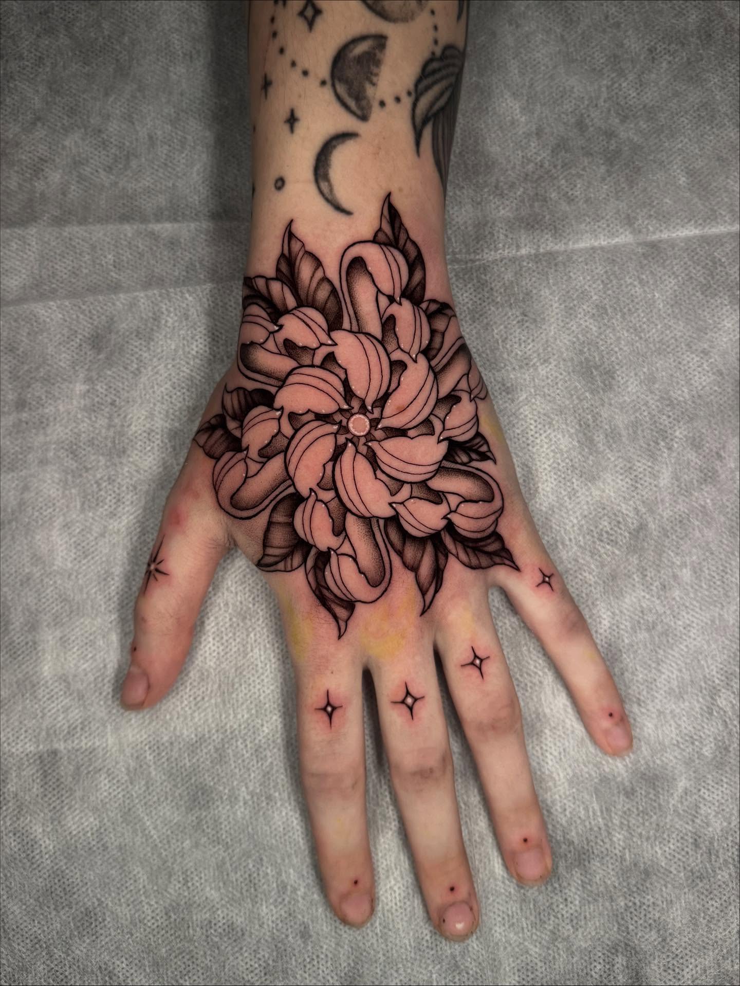 Chrysanthemum black and grey tattoo on the hand by kelsey hackett