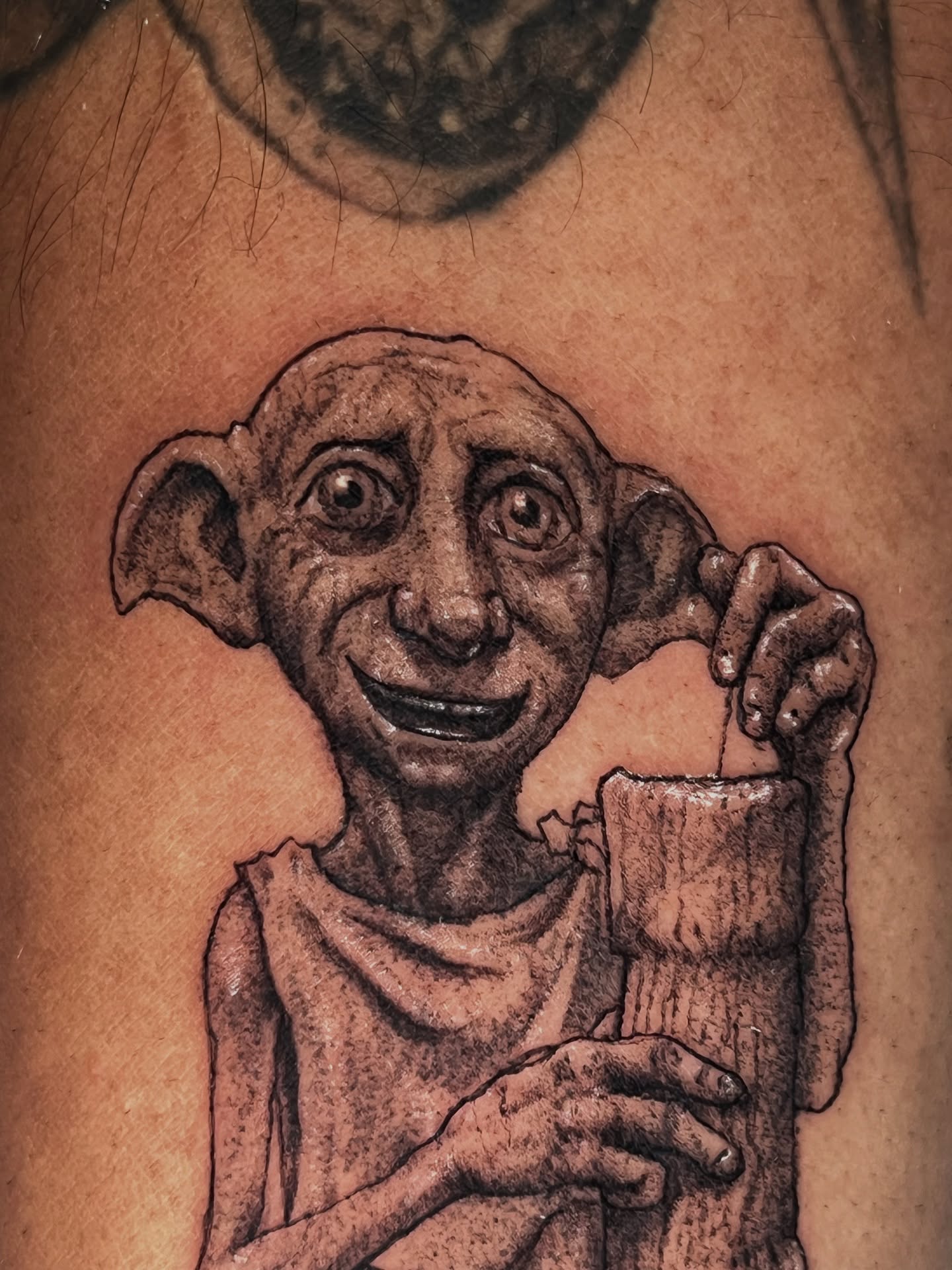 Dobby realism tattoo on the upper arm by Dotwork