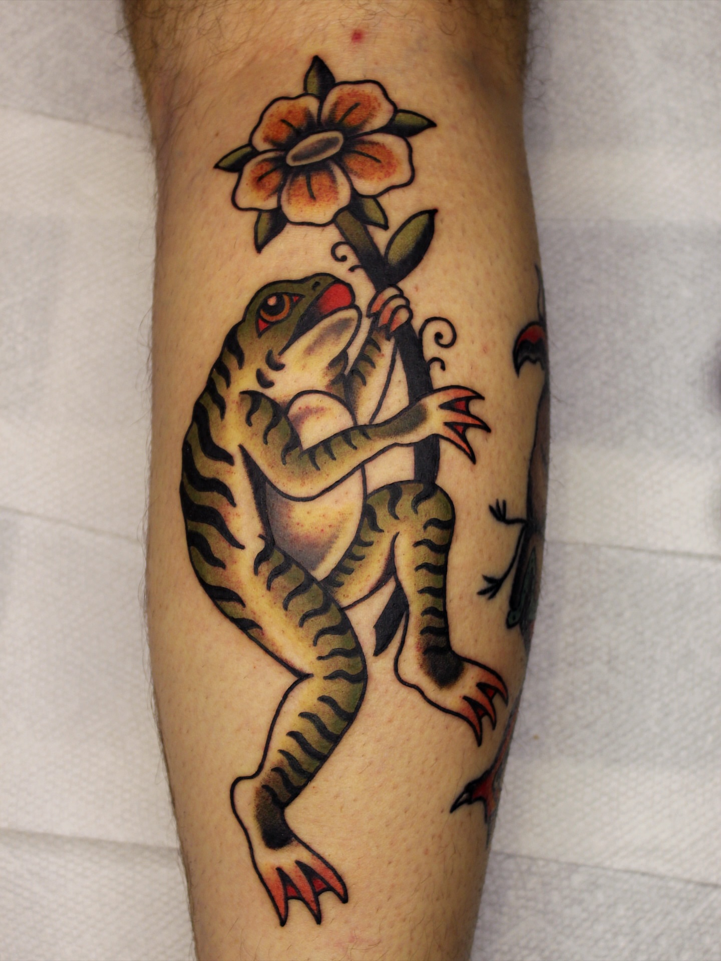 Frog and flower American traditional tattoo on the forearm by Kehrmie Tattoos, Berkeley, California