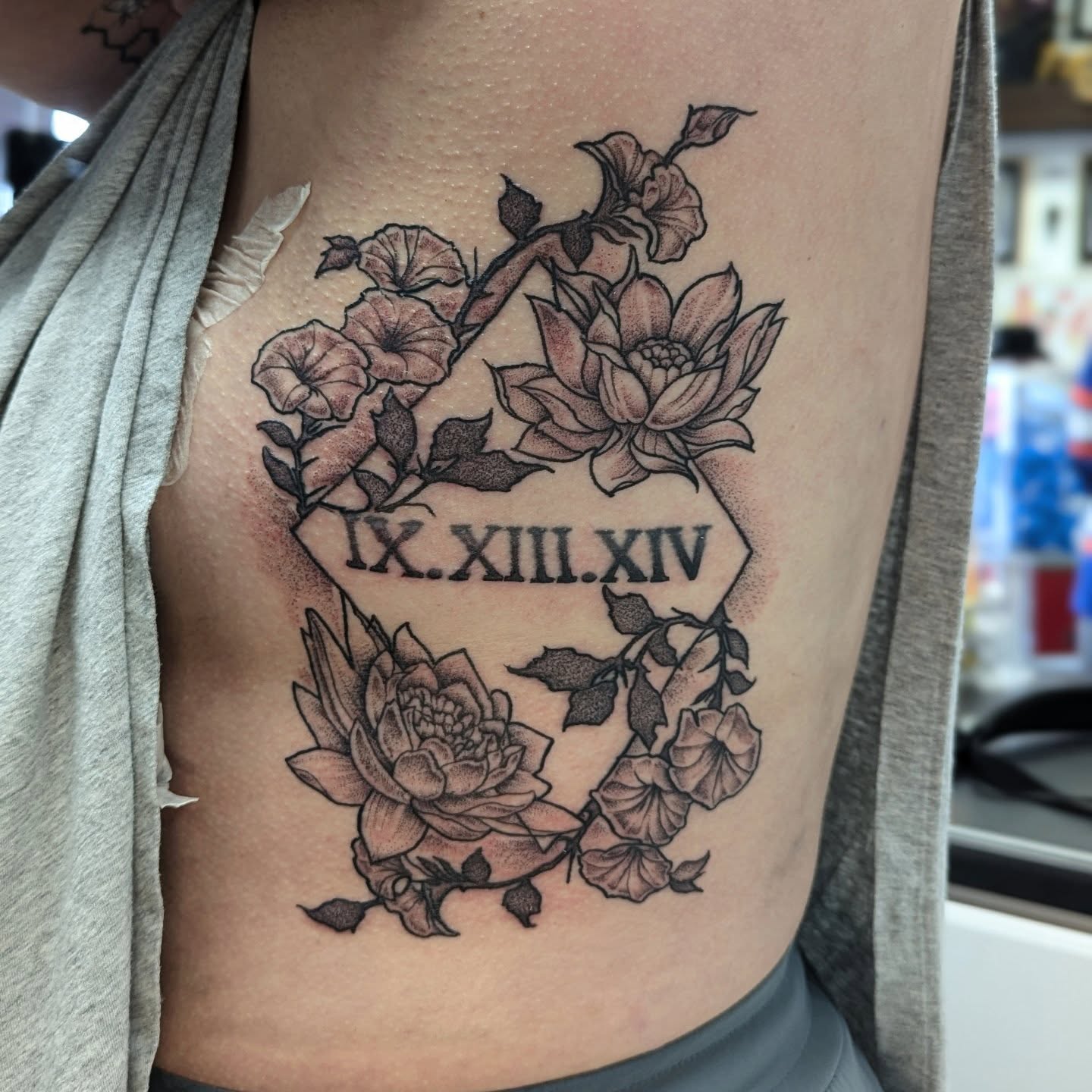 Lotus flowers and Roman numerals black and grey tattoo on the ribs by DONEL 📍Denver