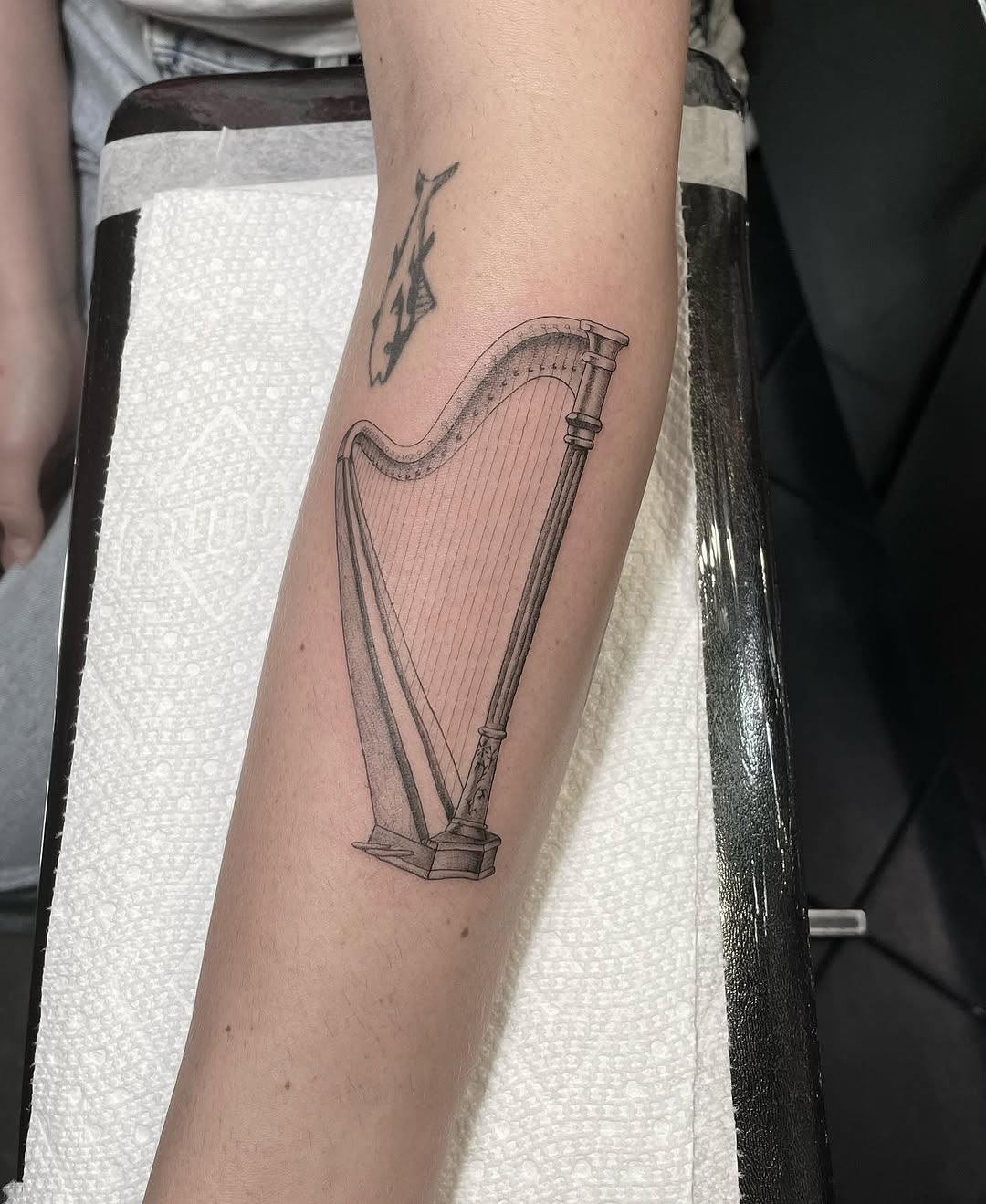 Harp minimalist tattoo on the forearm by Jesus A.