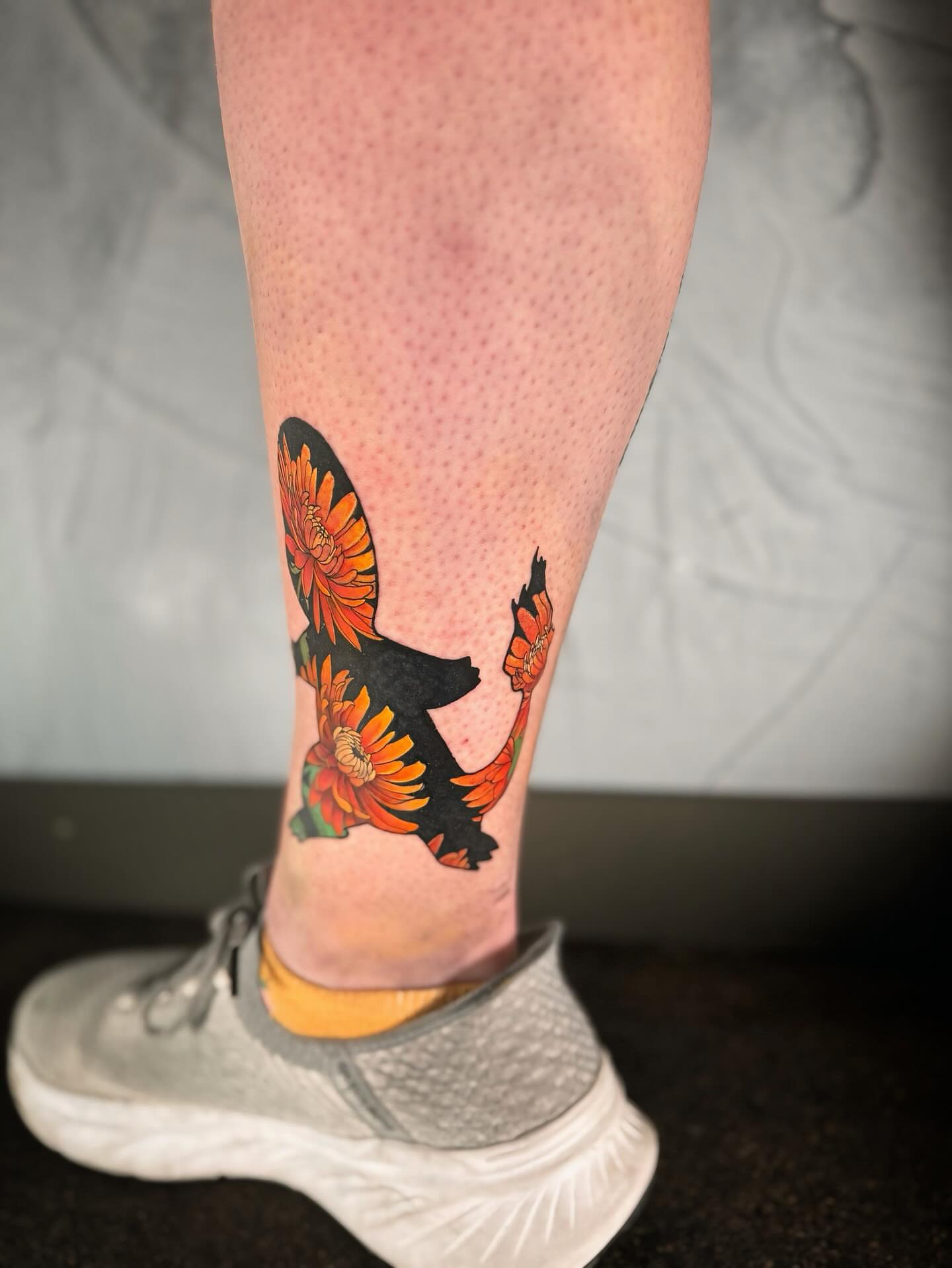 Bird with flowers American traditional tattoo on the calf by Ethan Lund