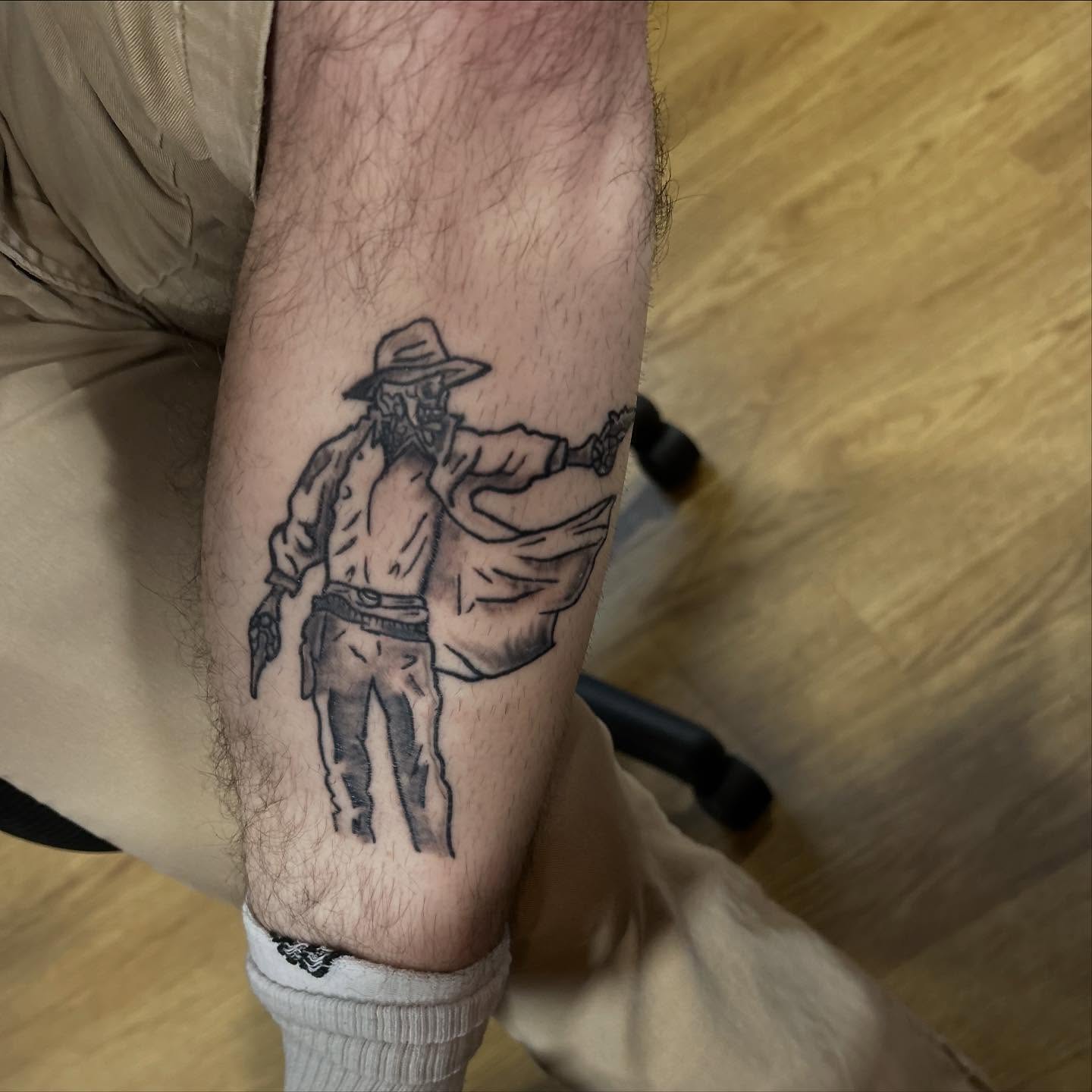 Cowboy with gun black and grey tattoo on the forearm by Luke