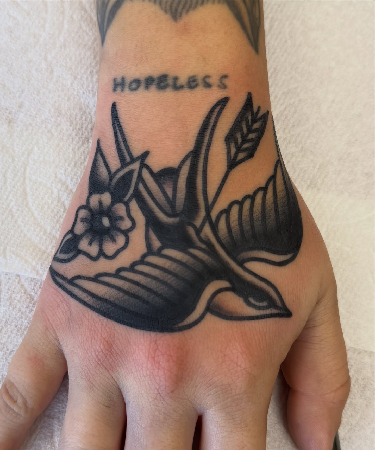 Swallow and flower American traditional tattoo on the hand by Joey Burdette Tattoos