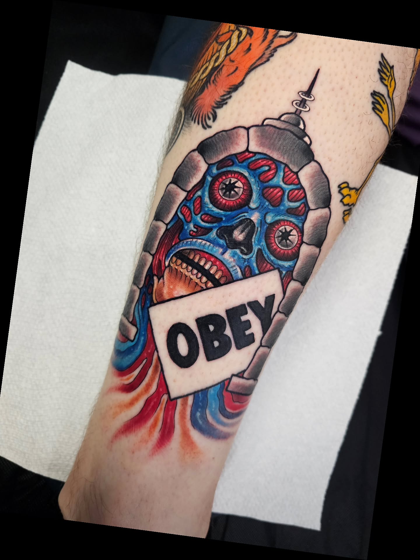 Skull with 'OBEY' banner American traditional tattoo on the forearm by Shannon