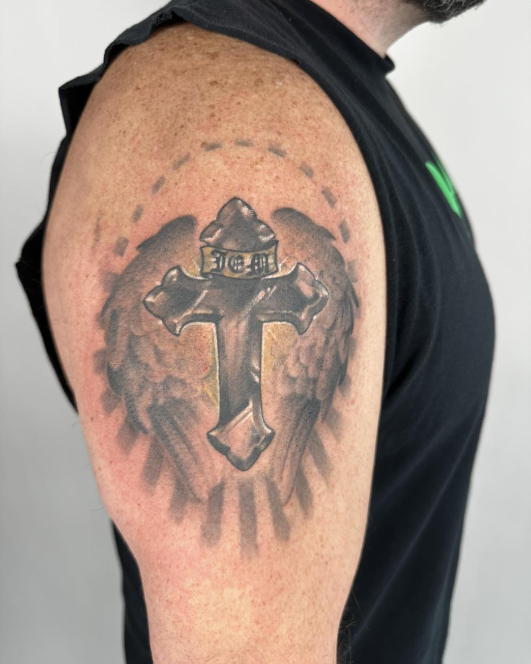 Cross with hat black and grey tattoo on the shoulder by Tattoos by Aeron Herald Maurbjorn, Sioux
