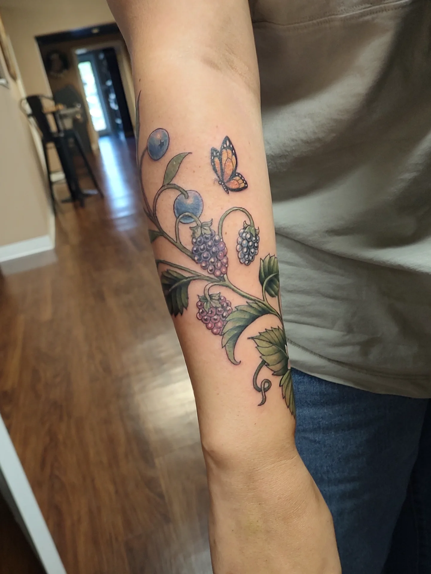 Berry vine with butterfly realism tattoo on the forearm by Jennifer Fowler