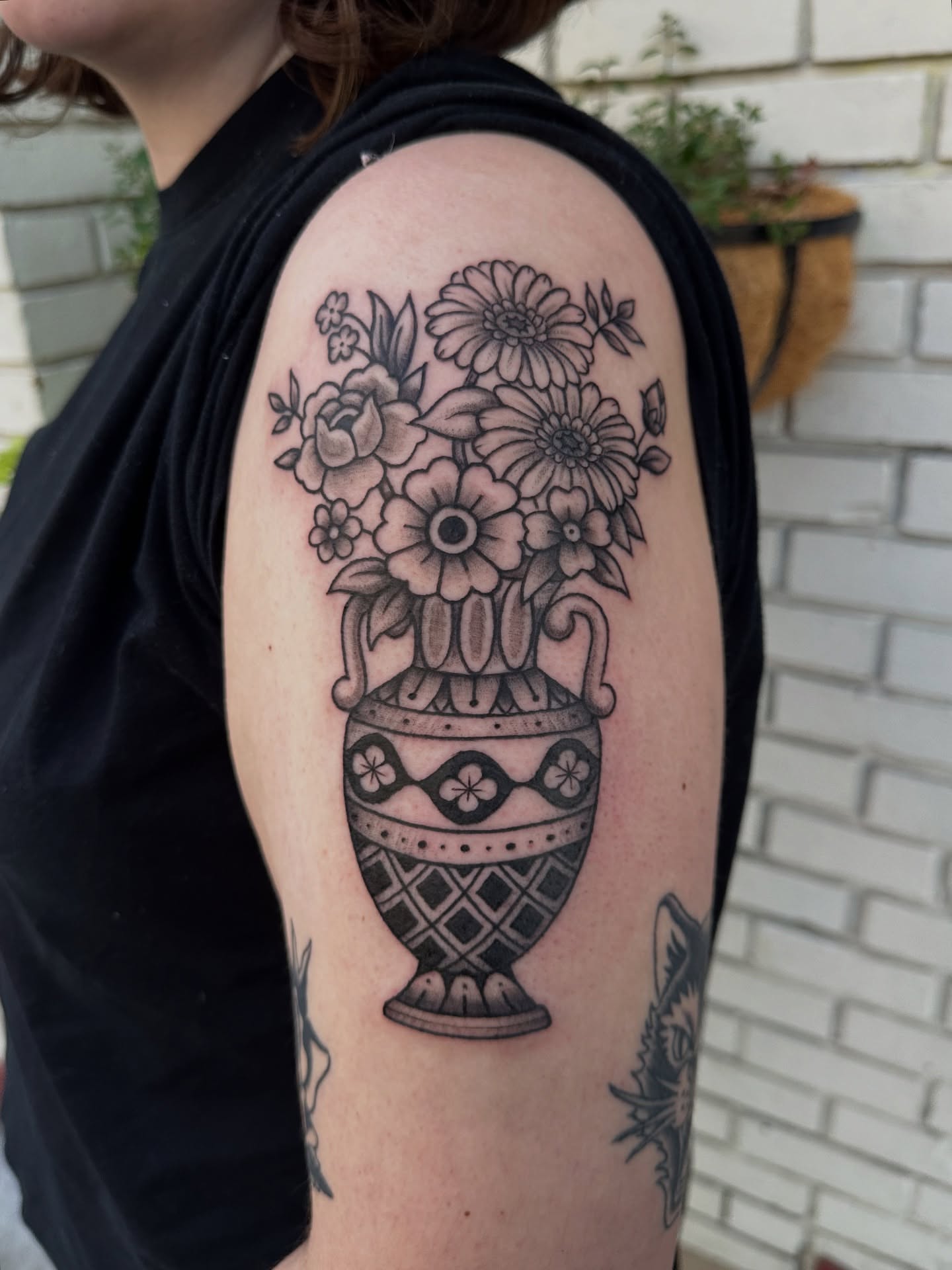 Flower vase black and grey tattoo on the upper arm by Lauren DeLizza