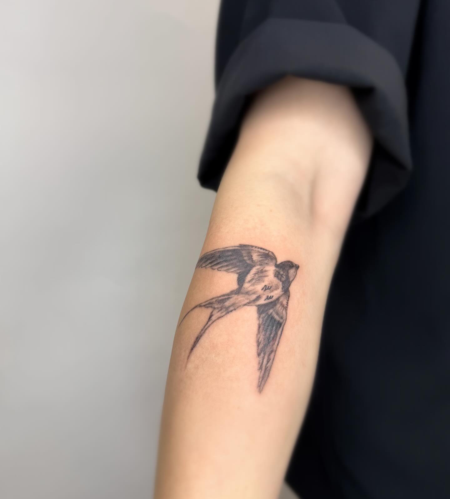 Swallow black and grey tattoo on the forearm by Joey tattoo