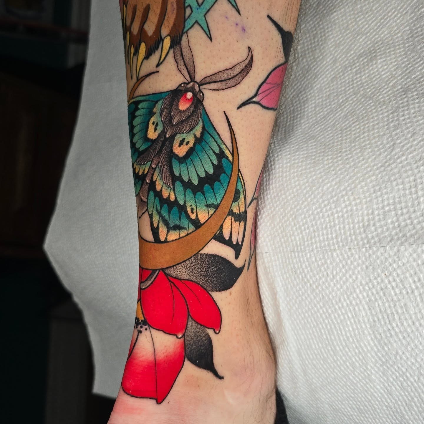 Butterfly and flower American traditional tattoo on the forearm by Justin Eldridge