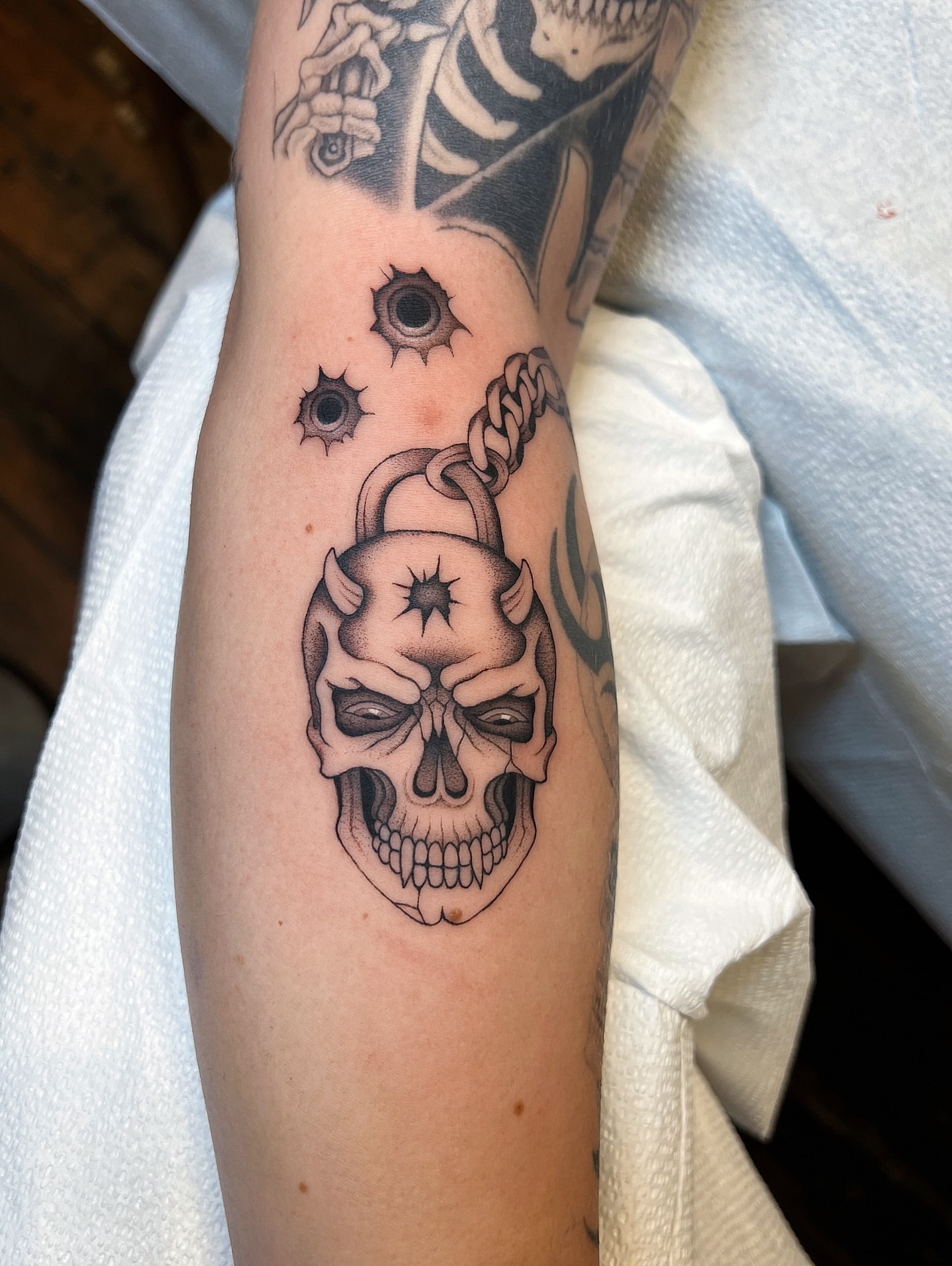 Skull with chain black and grey tattoo on the forearm by Mickey