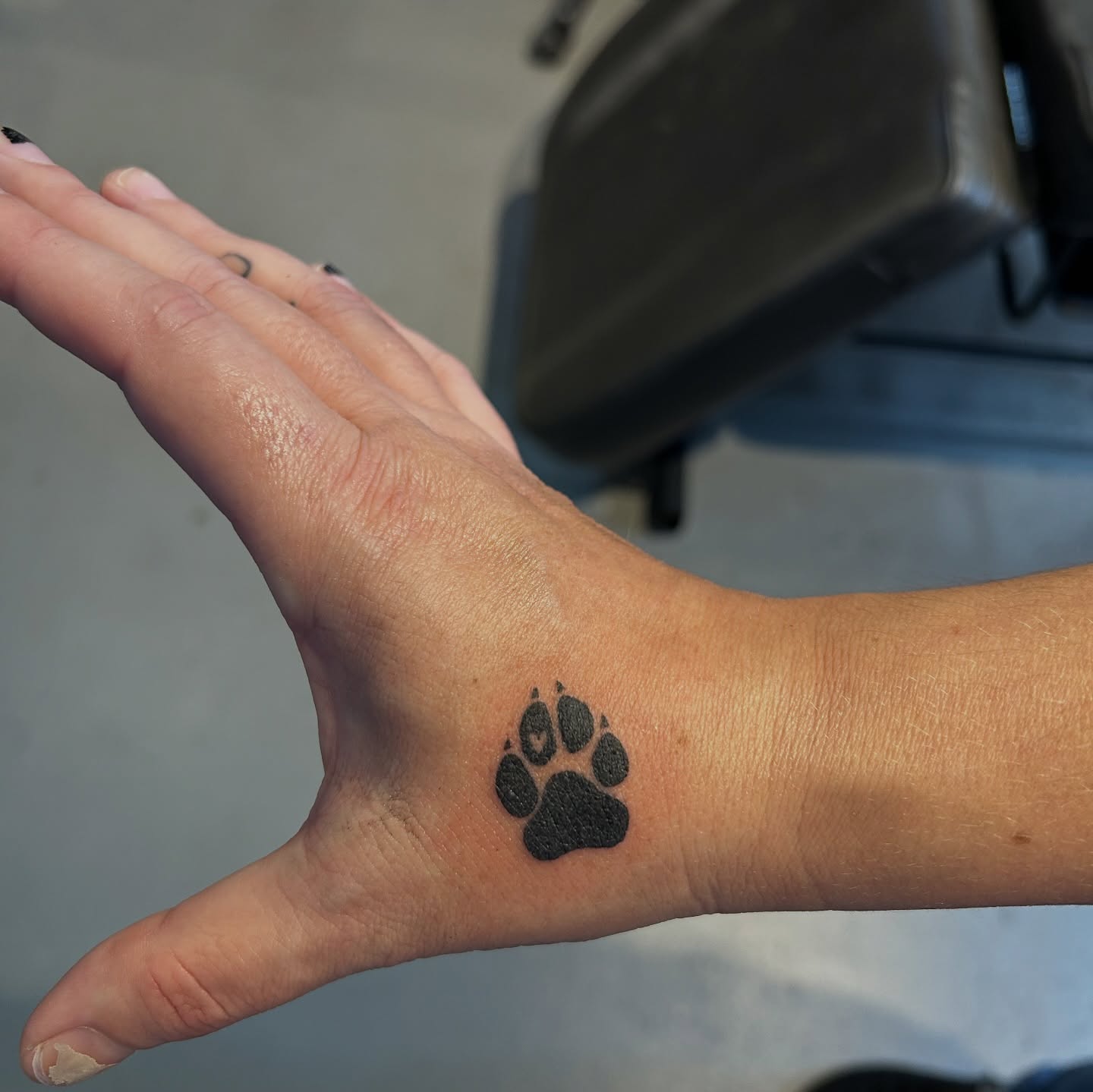 Paw print black and grey tattoo on the hand by @inkspirationtattoo_co