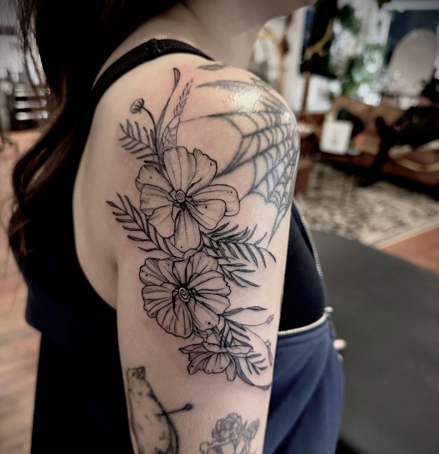 Flowers and spider web black and grey tattoo on the upper arm by Christen Wolfe CA Tattooer