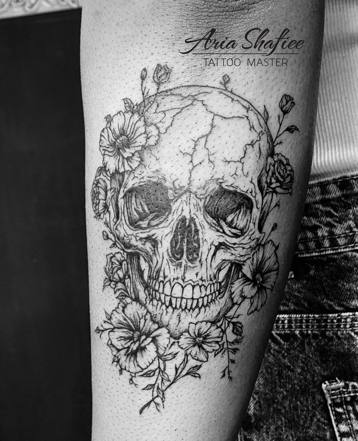 Skull with flowers realism tattoo on the forearm by Aria Shafiee