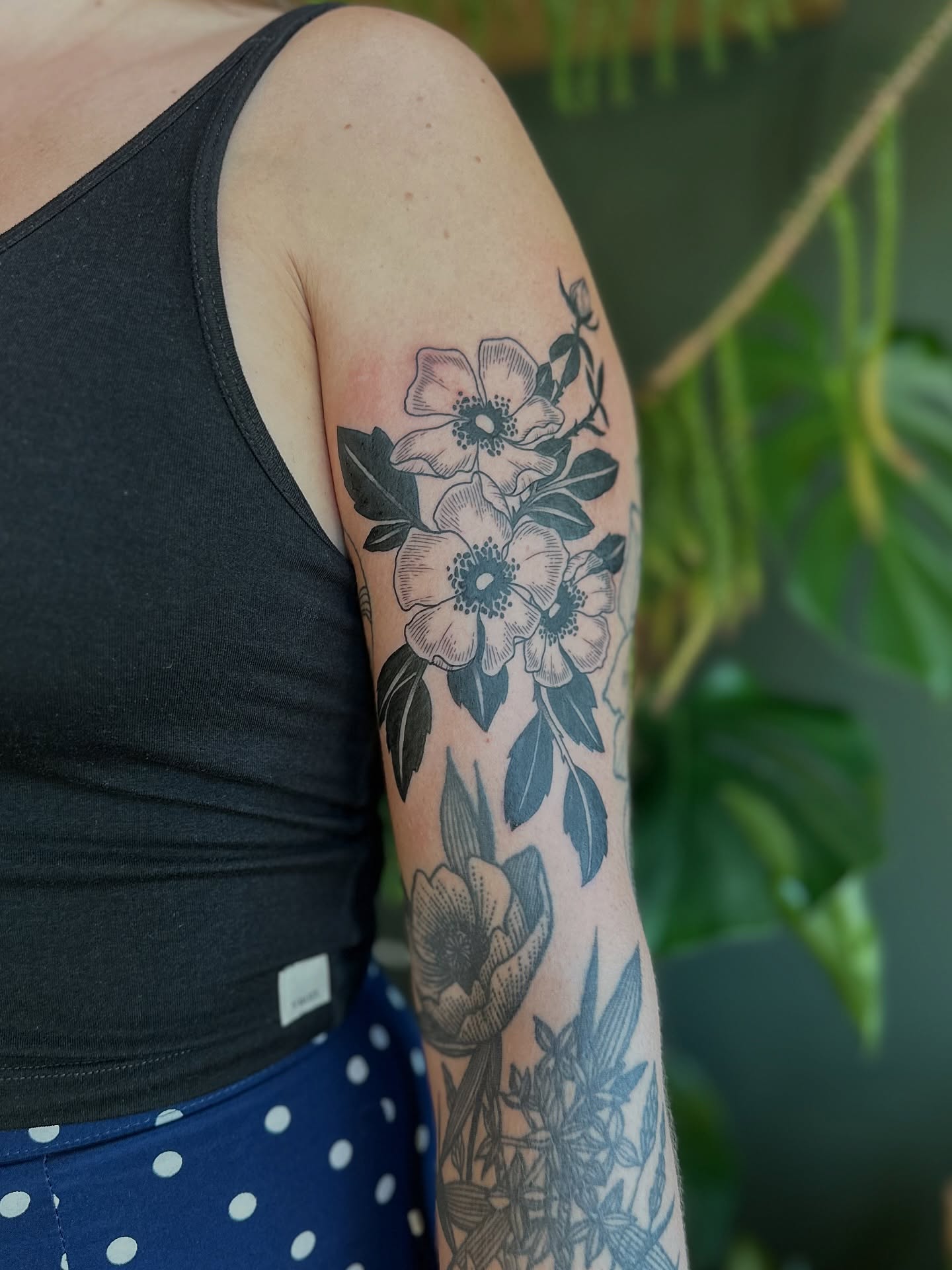 Floral bouquet black and grey tattoo on the upper arm by Alexandra Gray