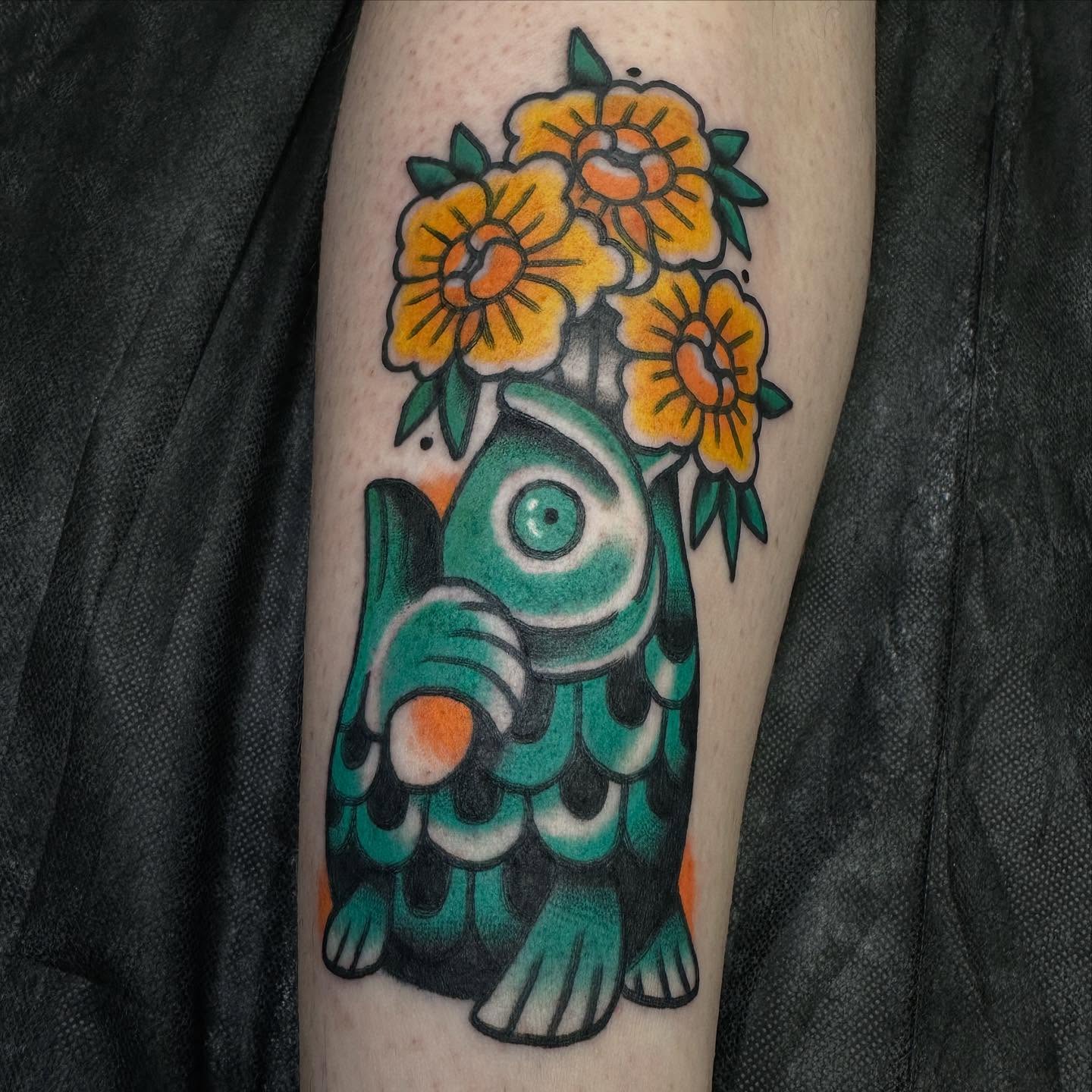 Fish with flowers American traditional tattoo on the forearm by Hannah Jean