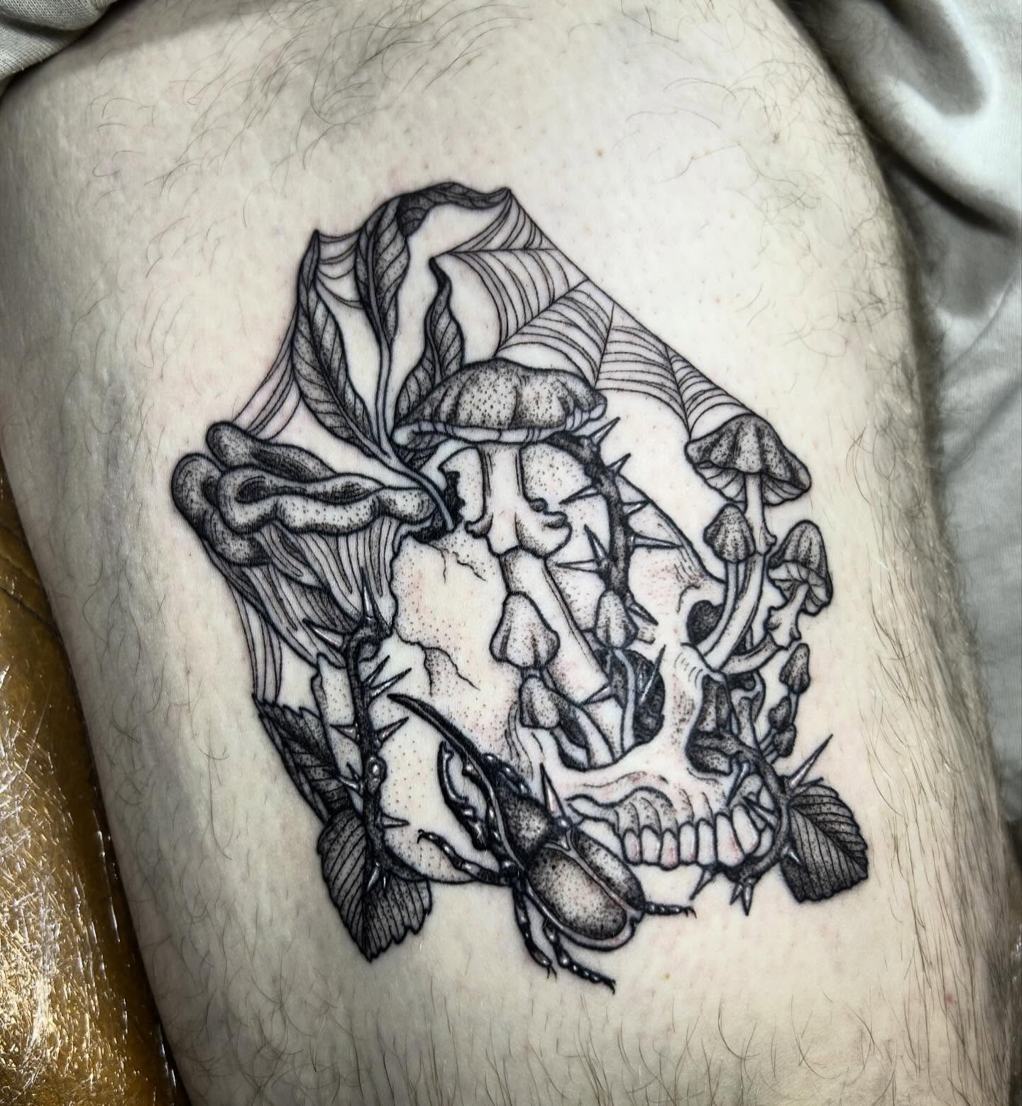 Skull with mushrooms dotwork tattoo on the thigh by Nikki Power