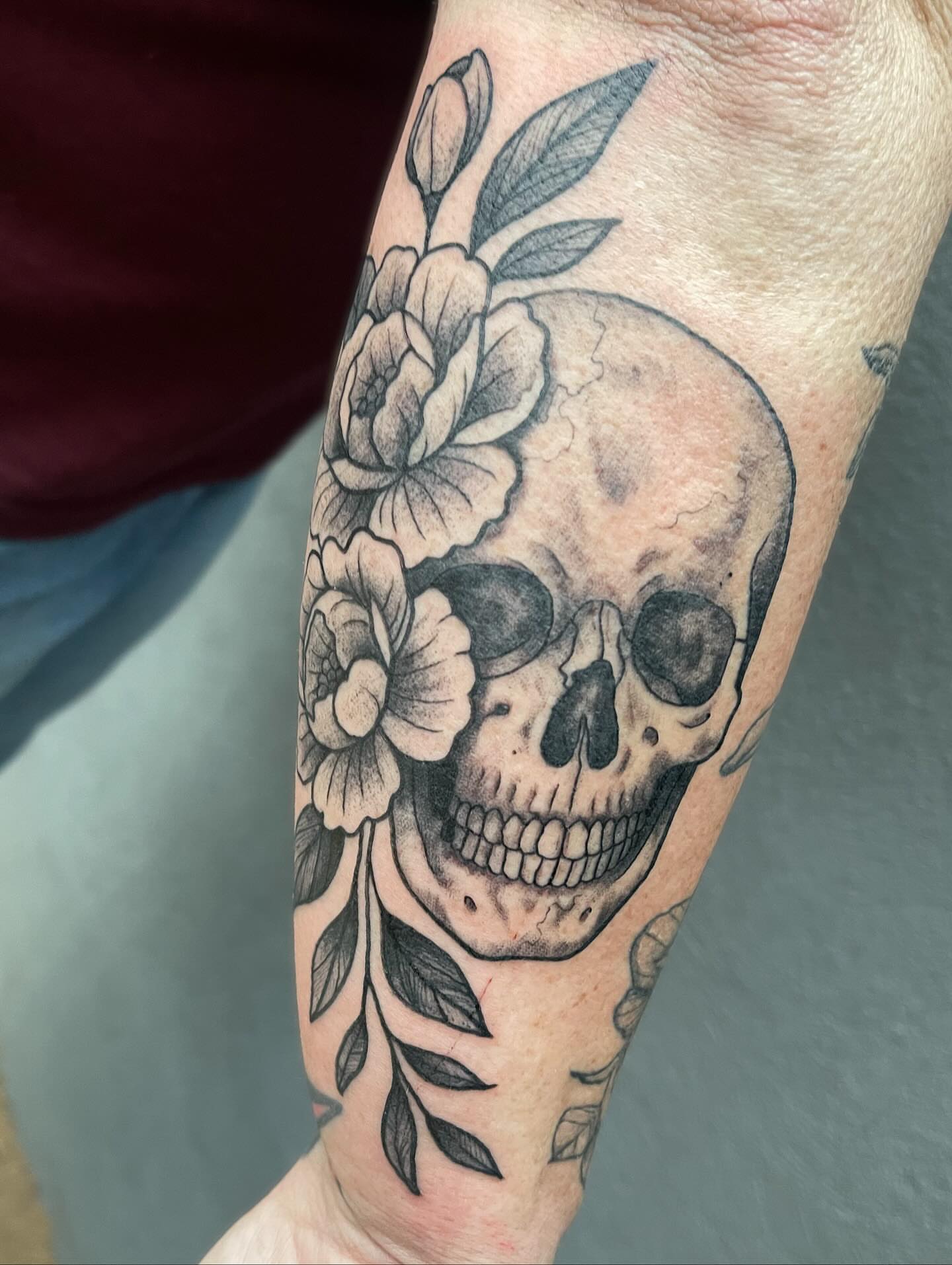 Skull and flowers realism tattoo on the forearm by Josh Brownell