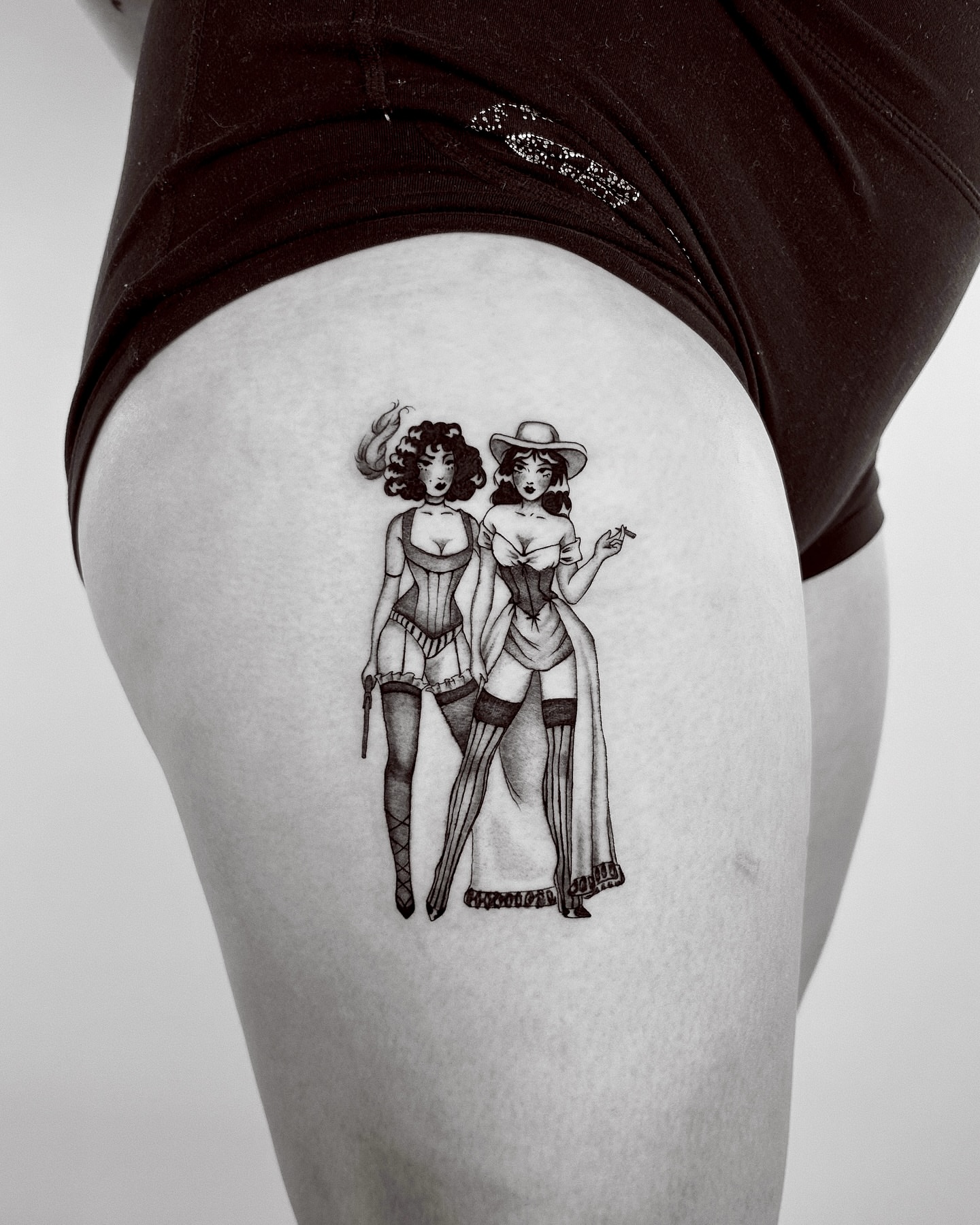 Cowgirl duo black and grey tattoo on the thigh by Montana Chambers