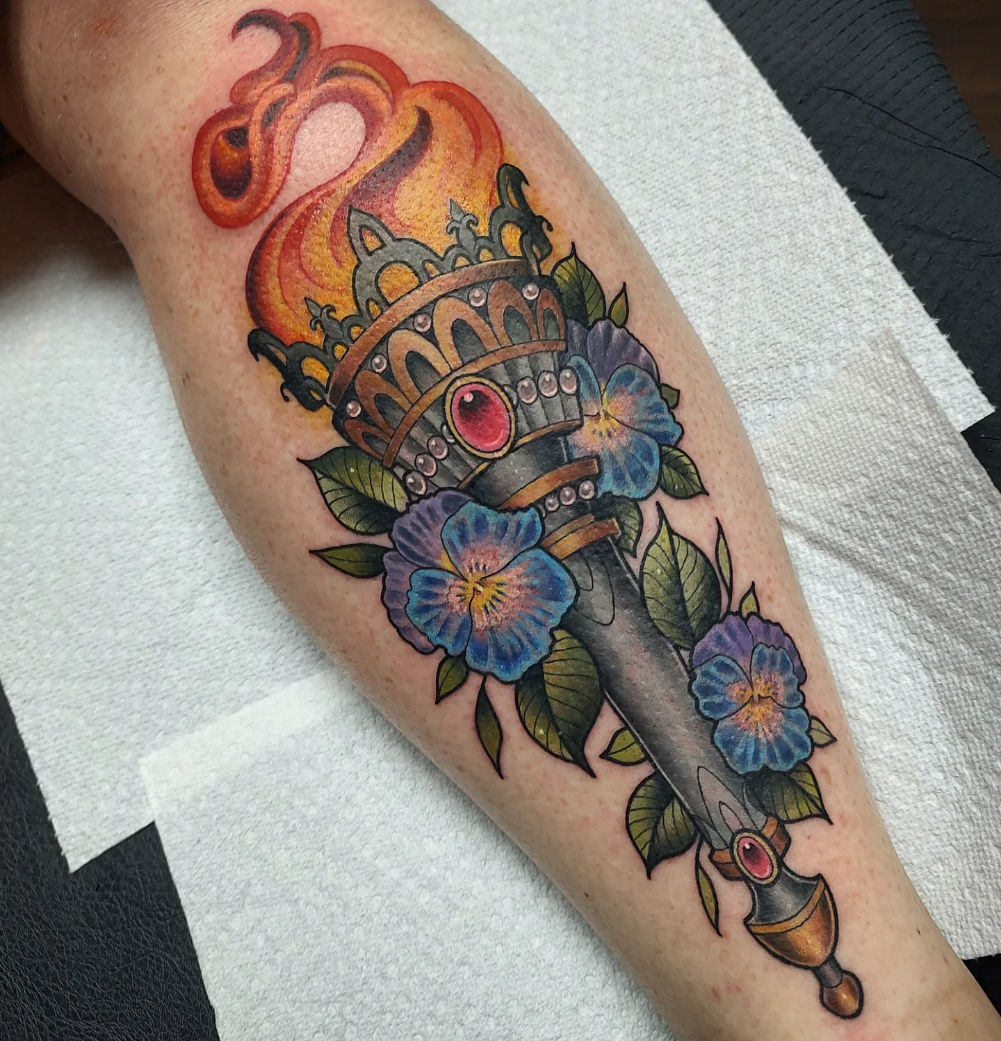 Sword with crown and flowers American traditional tattoo on the forearm by Jennifer Fowler
