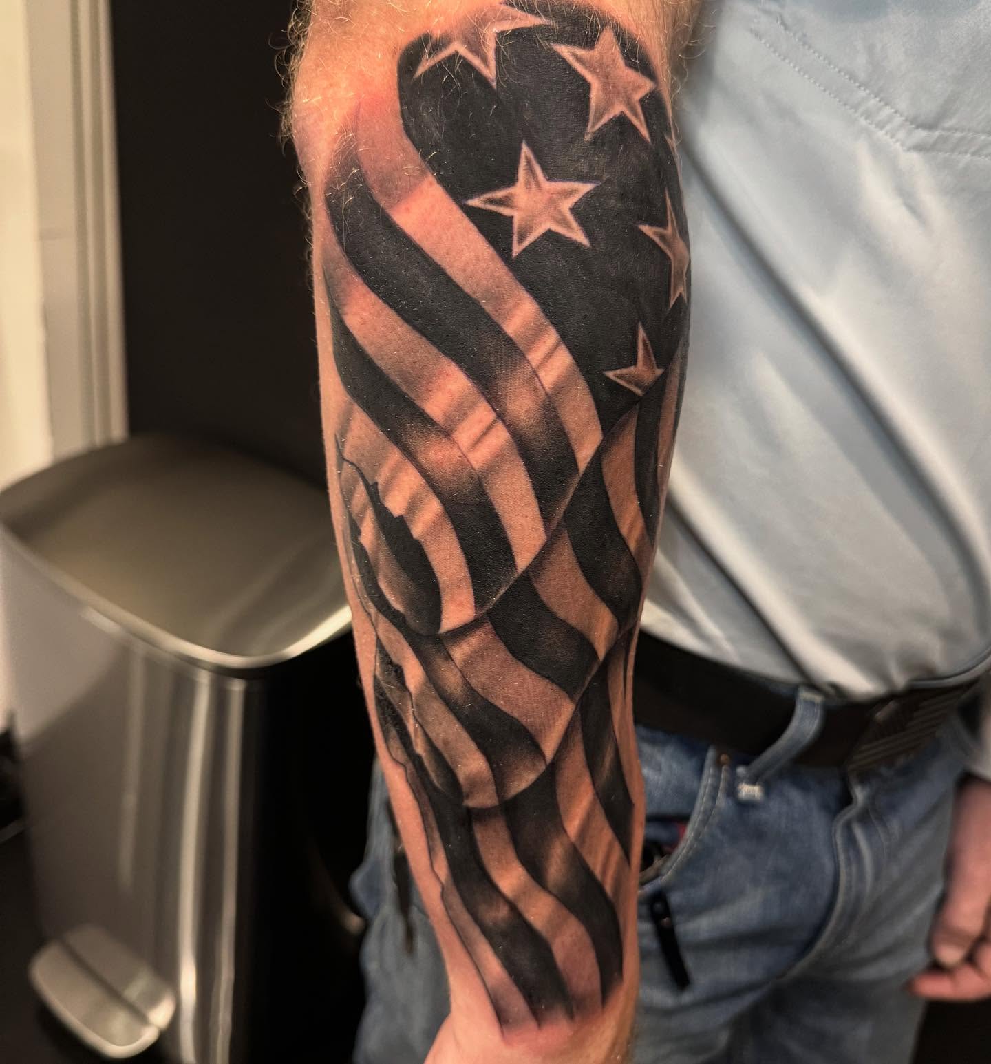 American flag black and grey tattoo on the forearm by Brian Herrera