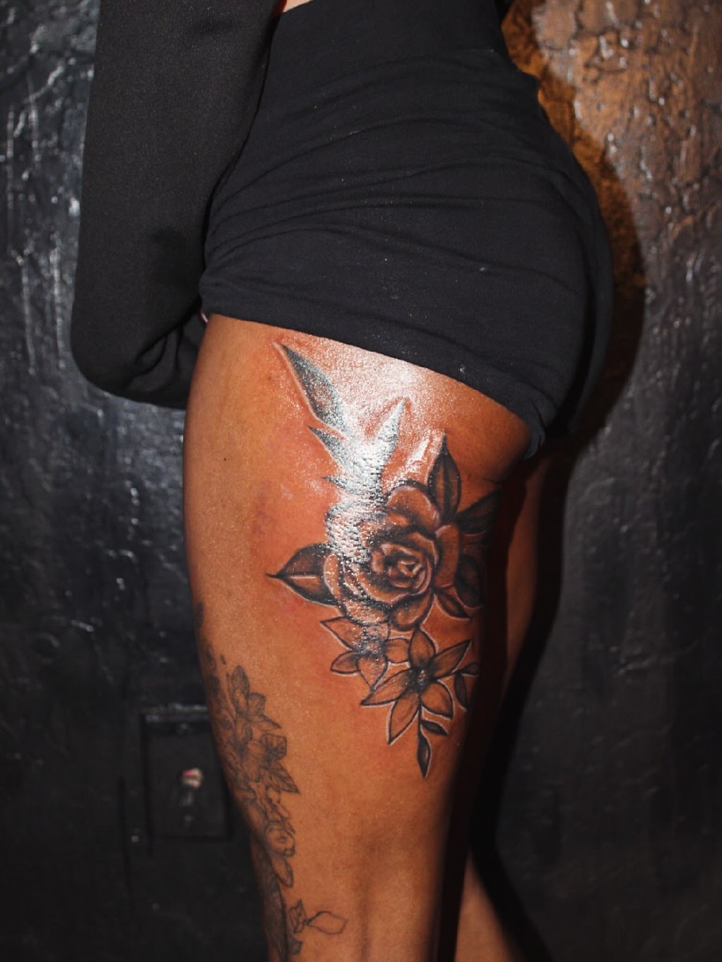 Rose and floral arrangement black and grey tattoo on the thigh by Gessel Leticia Enriquez