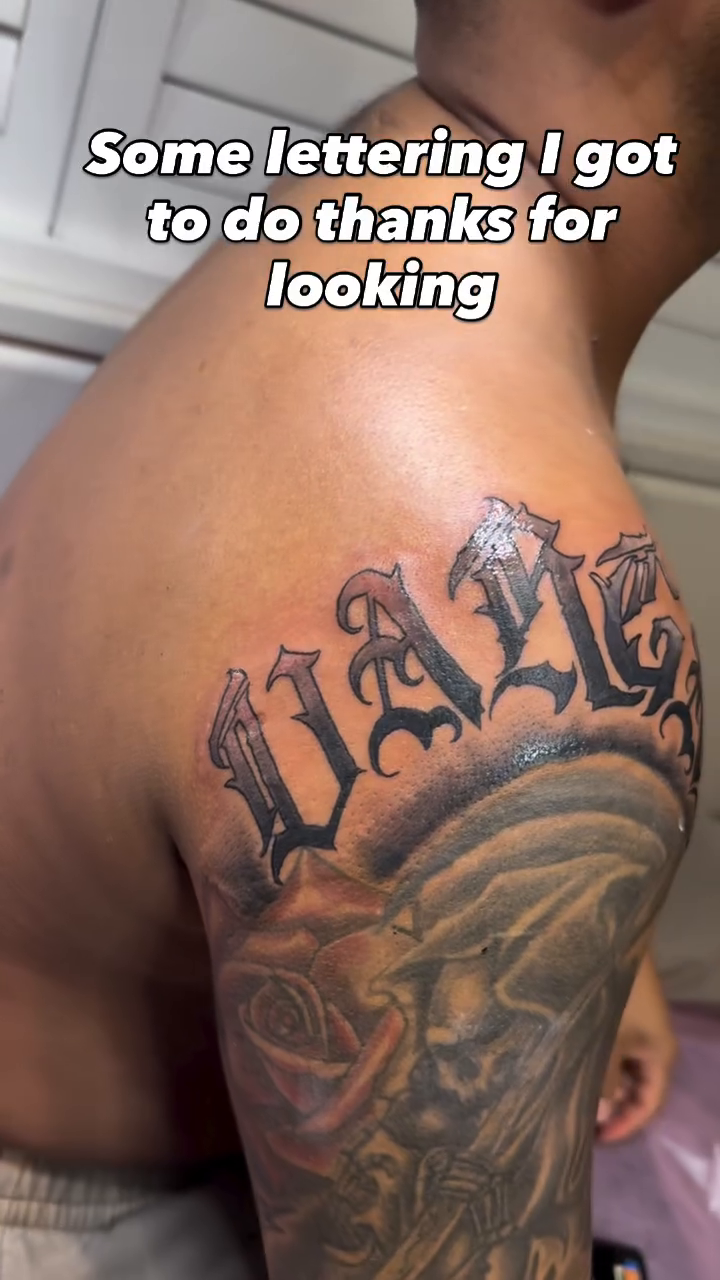 Lettering tattoo with angel wings Chicano tattoo on the upper arm by Jason Topliss
