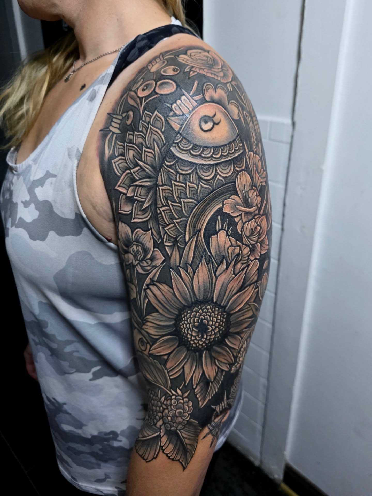 Koi fish and sunflower geometric tattoo on the upper arm by Michael Latendresse