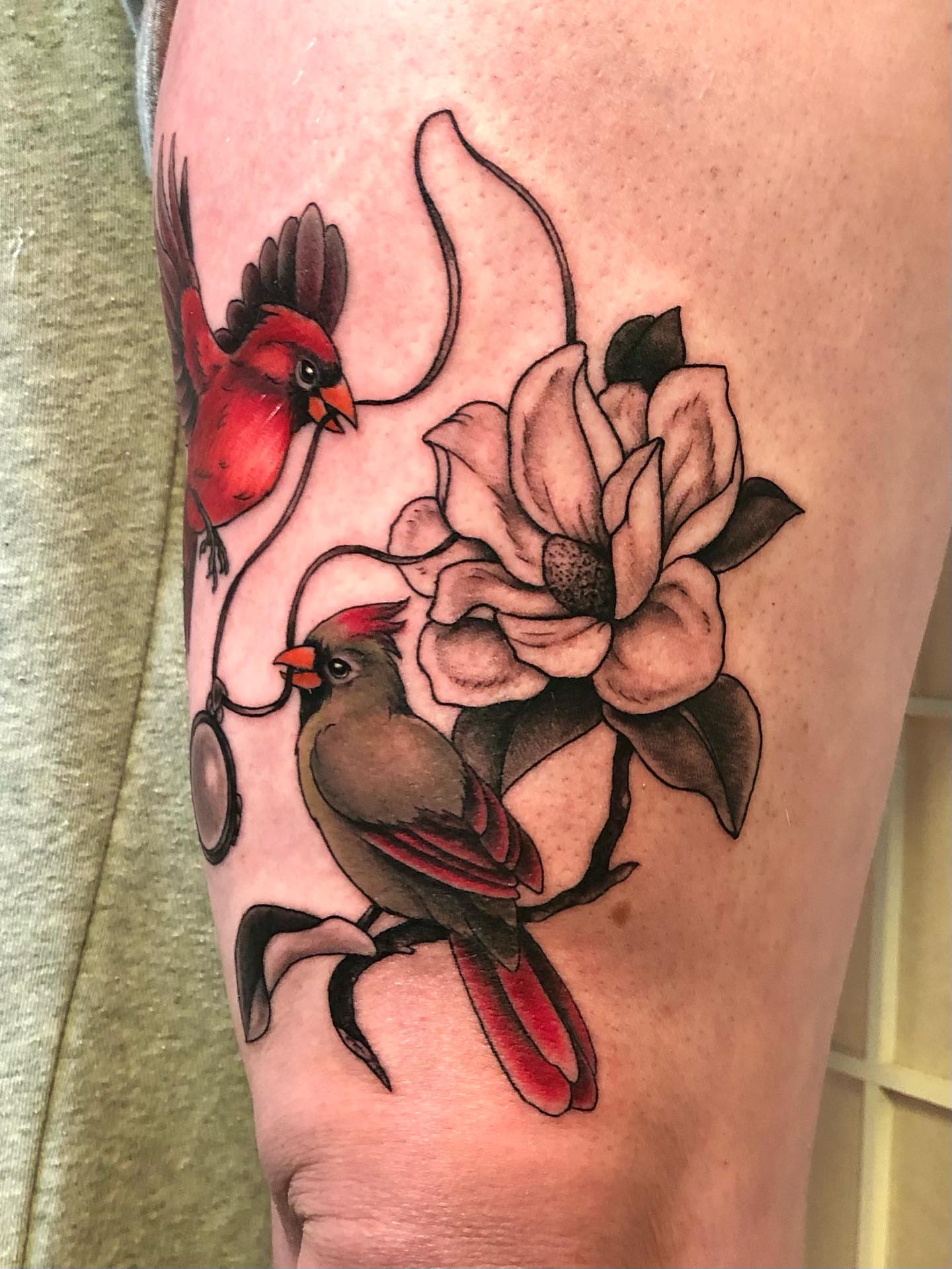 Cardinals and magnolia realism tattoo on the thigh by Leah Leinani