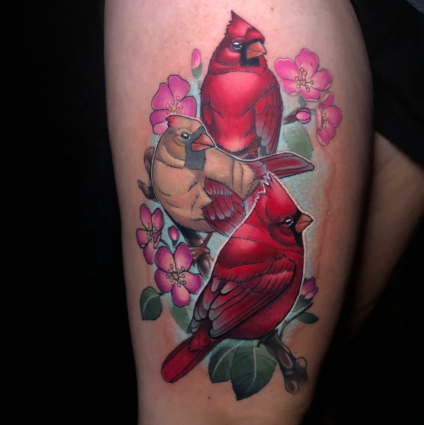 Cardinals and flowers realism tattoo on the thigh by Emily Walker
