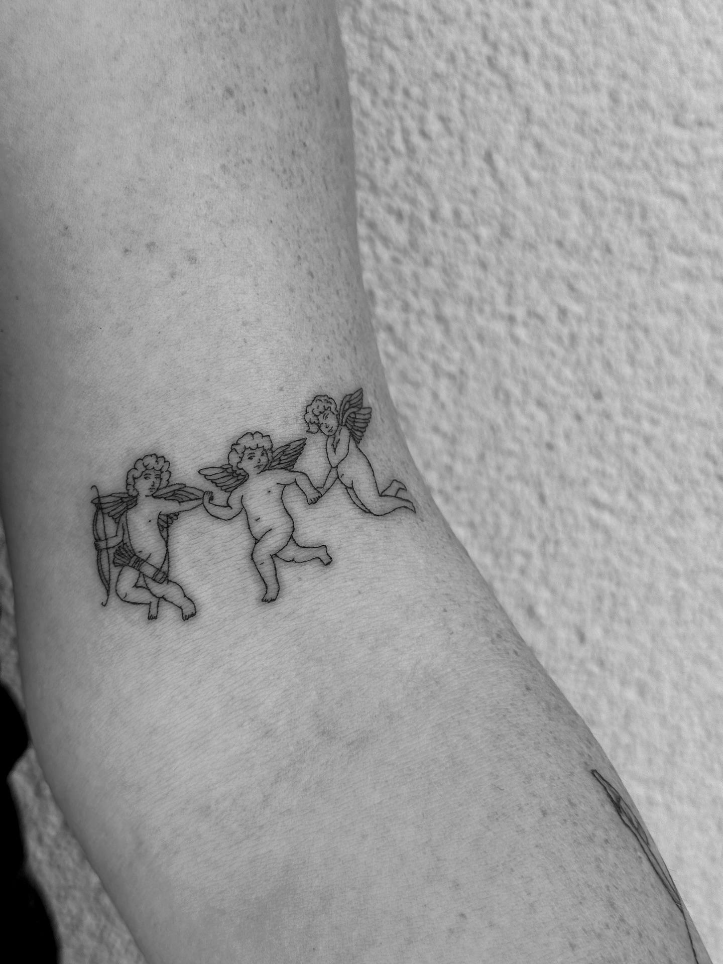 Cherubs black and grey tattoo on the forearm by Abby Robinson