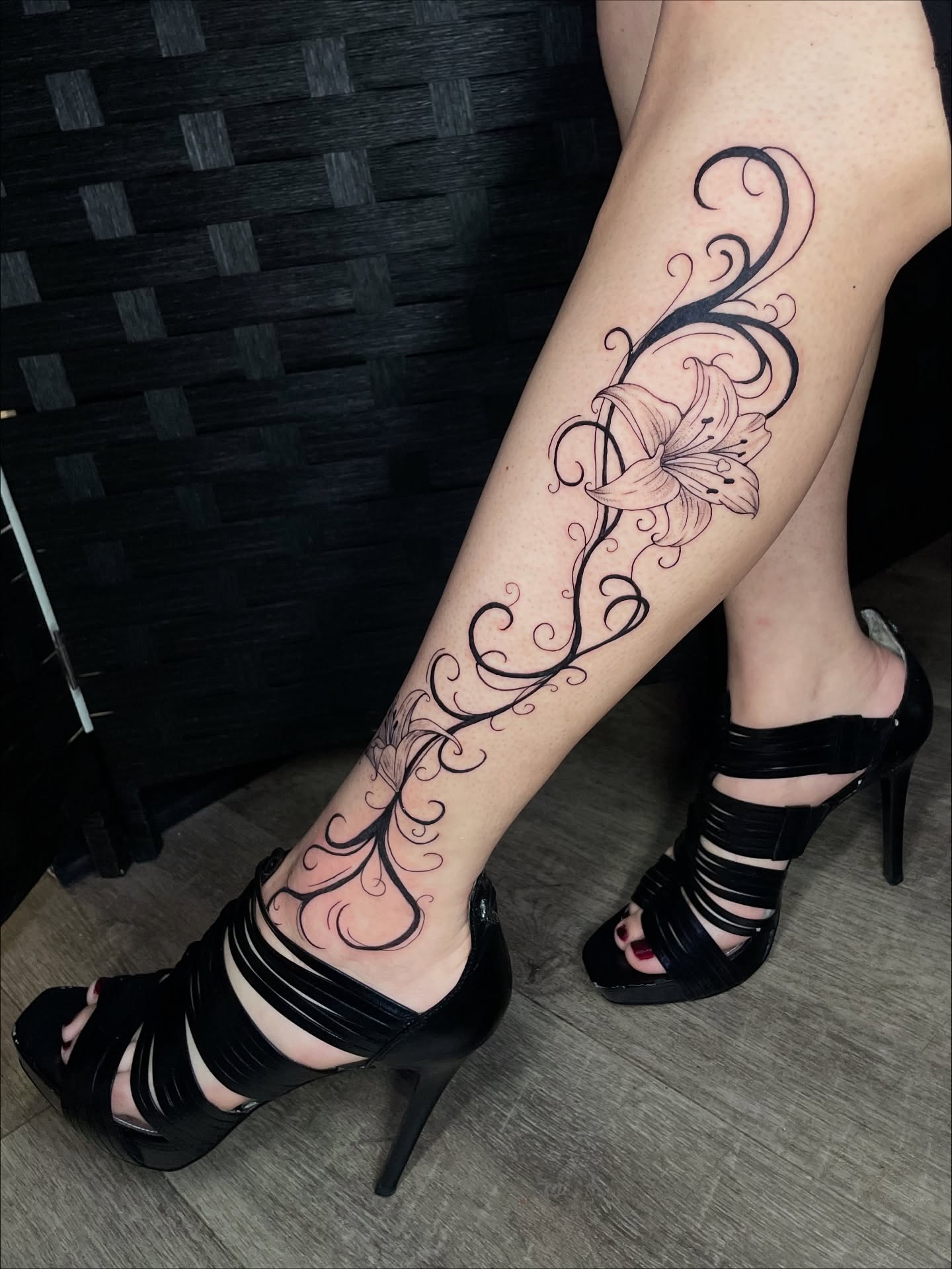 Lily and swirls black and grey tattoo on the calf by Sophia Tattoo