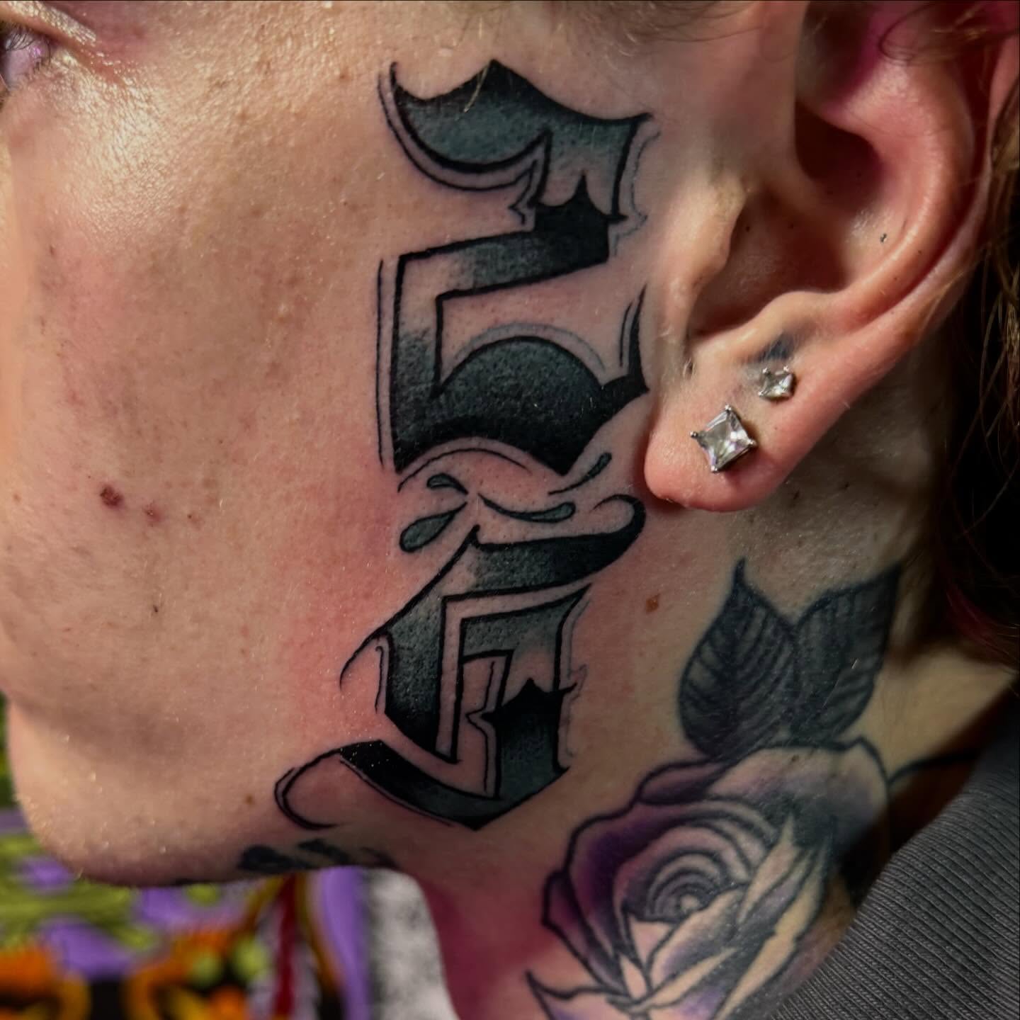 Letter E black and grey tattoo on the neck by Michael Latendresse