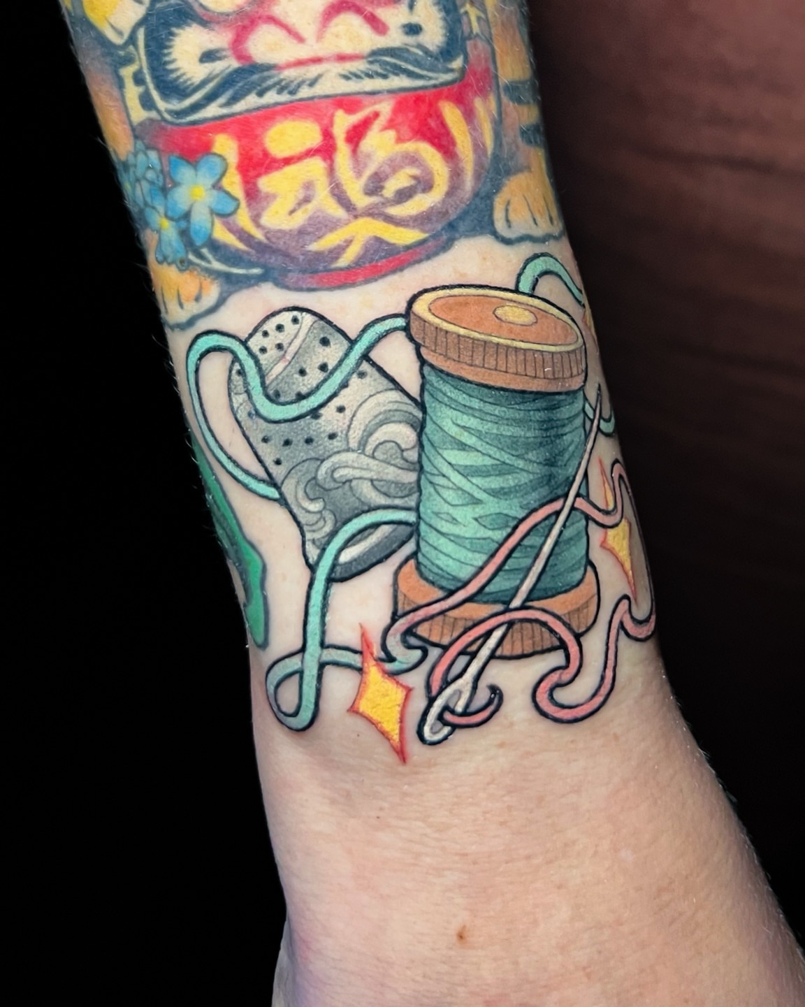 Thread spool and needle American traditional tattoo on the forearm by Hannah Steele