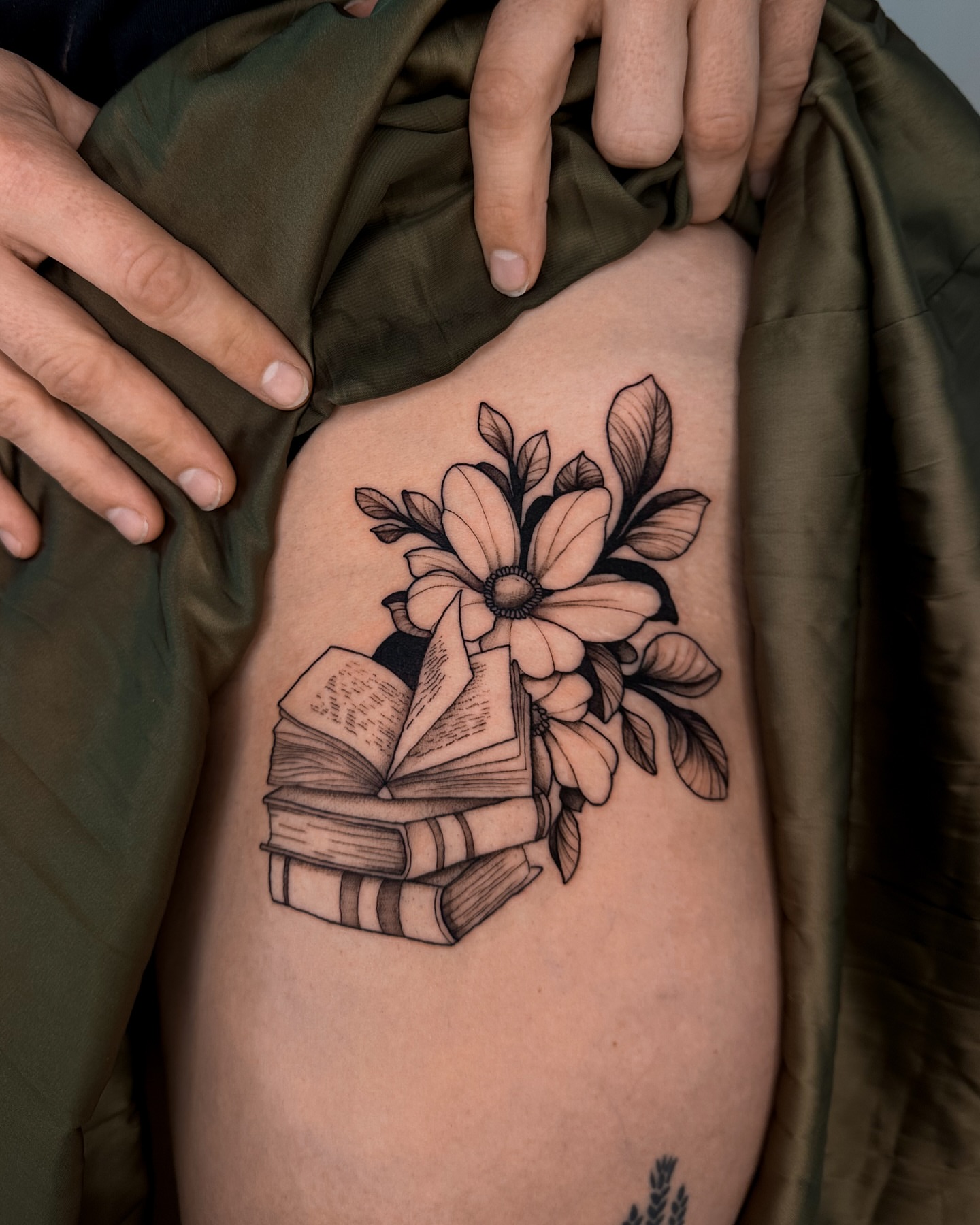 Book stack with flower black and grey tattoo on the thigh by Lauren