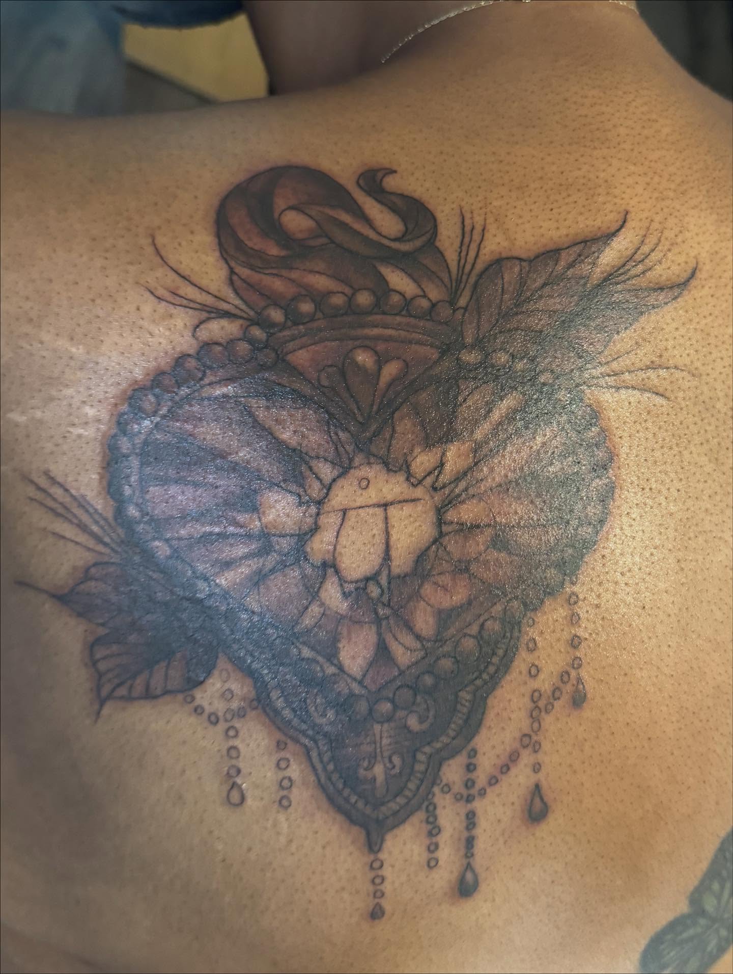 Heart with wings ornamental tattoo on the back by Gabe