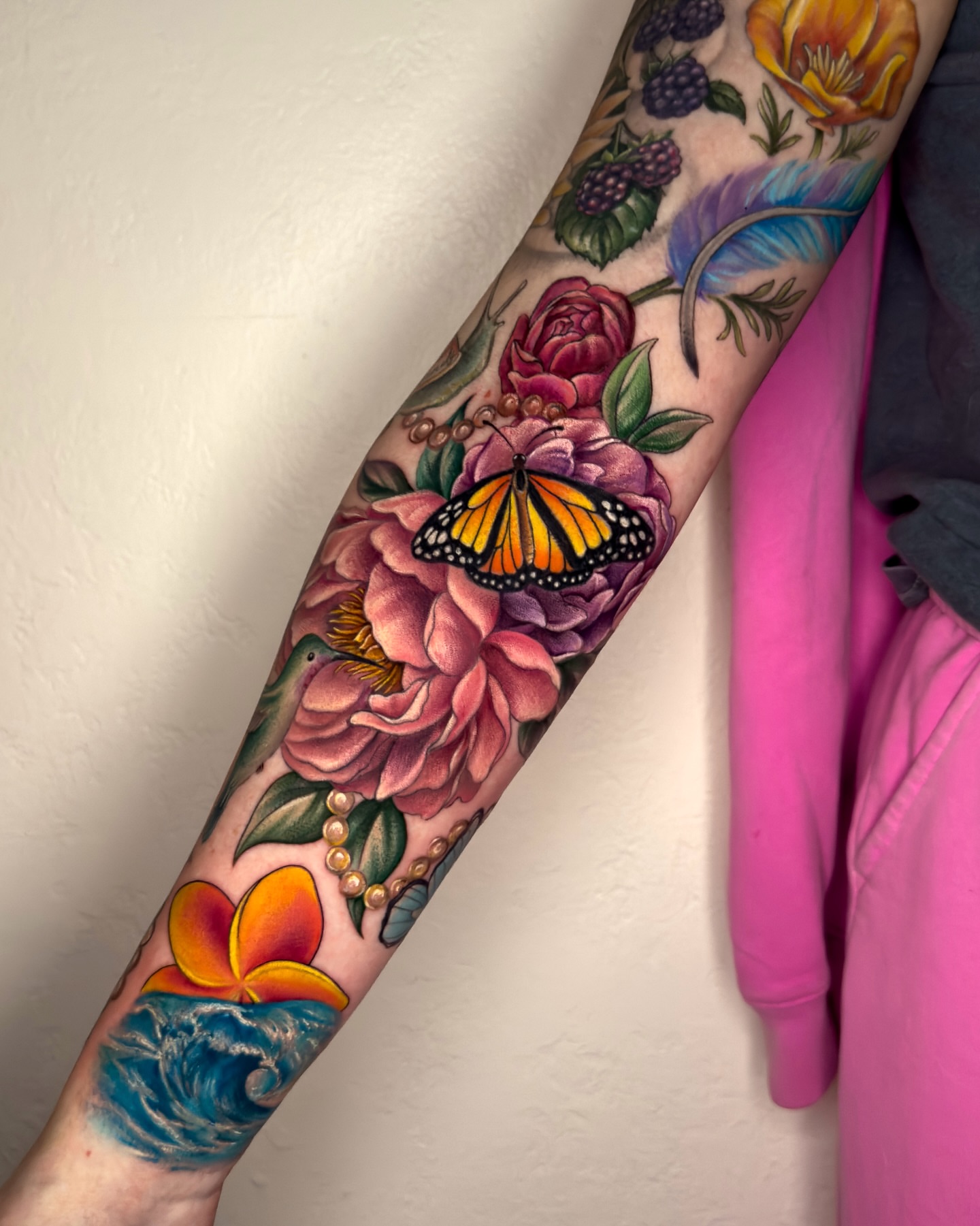 Floral bouquet with butterfly realism tattoo on the forearm by Nichole Lorence