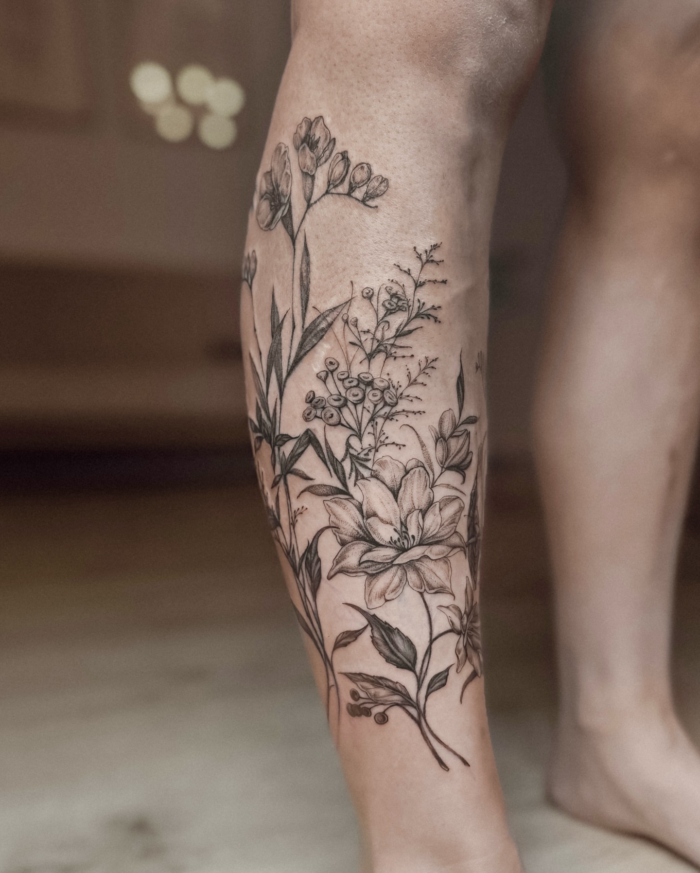 Floral arrangement black and grey tattoo on the calf by Ayauna Mai