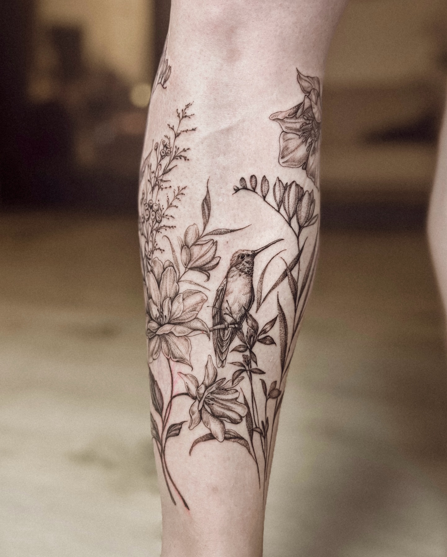 Bird and floral realism tattoo on the calf by Ayauna Mai
