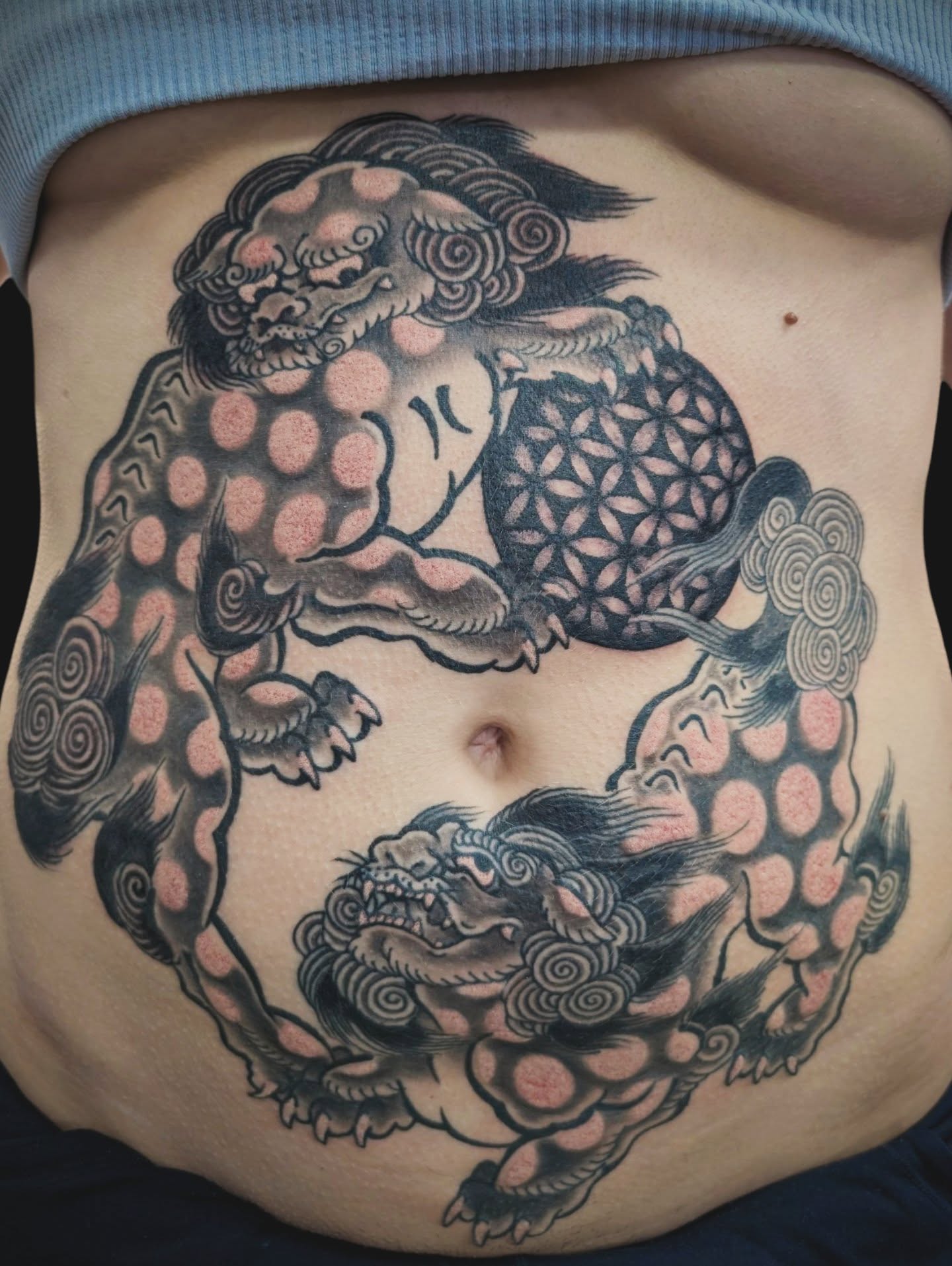 Lion and flower dotwork tattoo on the torso by Angela Mukai