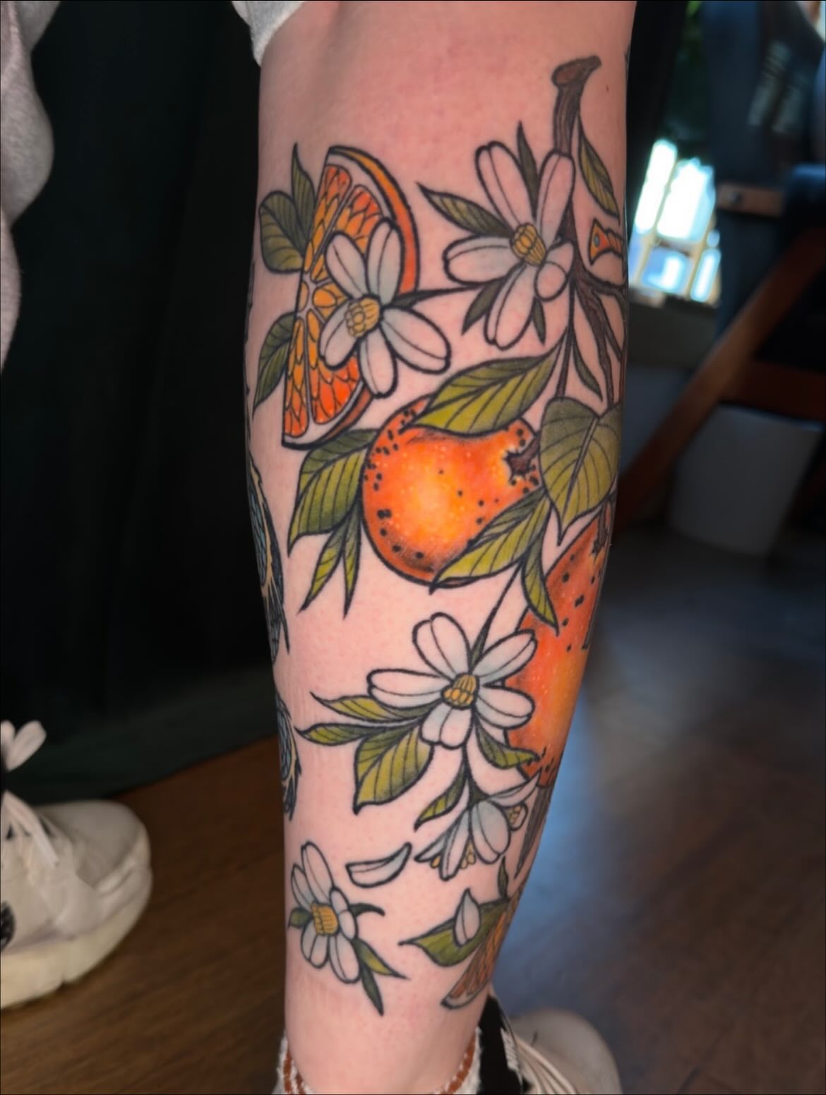Orange and flowers new school tattoo on the forearm by Jessica Haug