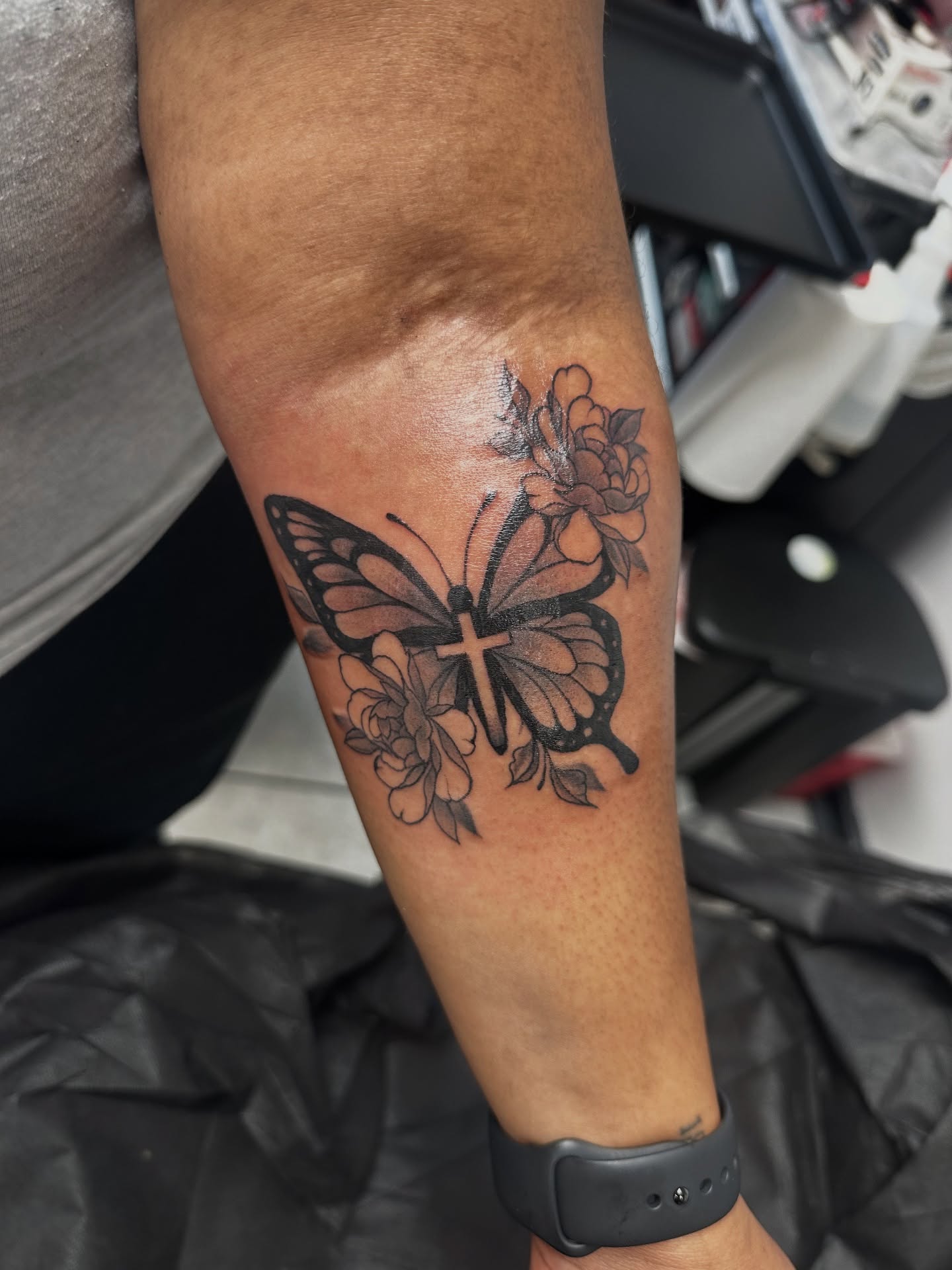 Butterfly and flowers black and grey tattoo on the forearm by Mia Layne 🤎