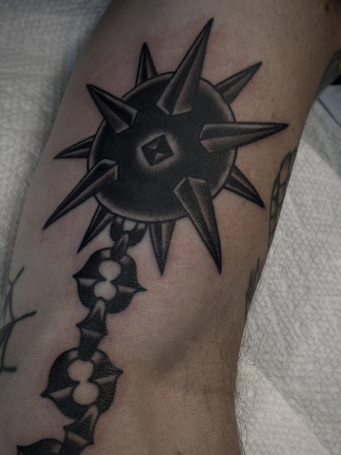 Spiked sun black and grey tattoo on the forearm by Carlos Gonzalez Tattoo, Dallas, Texas