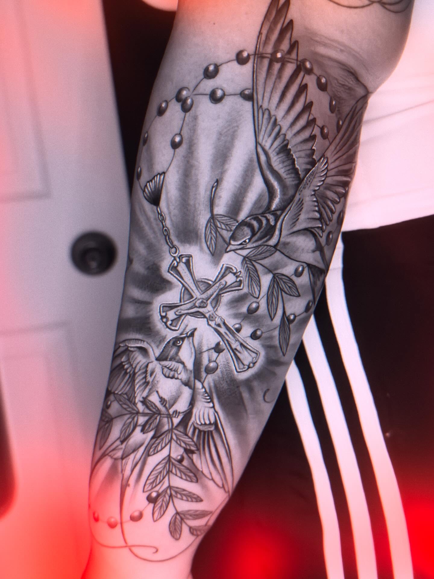 Cross and bird realism tattoo on the forearm by Eric Zuluaga