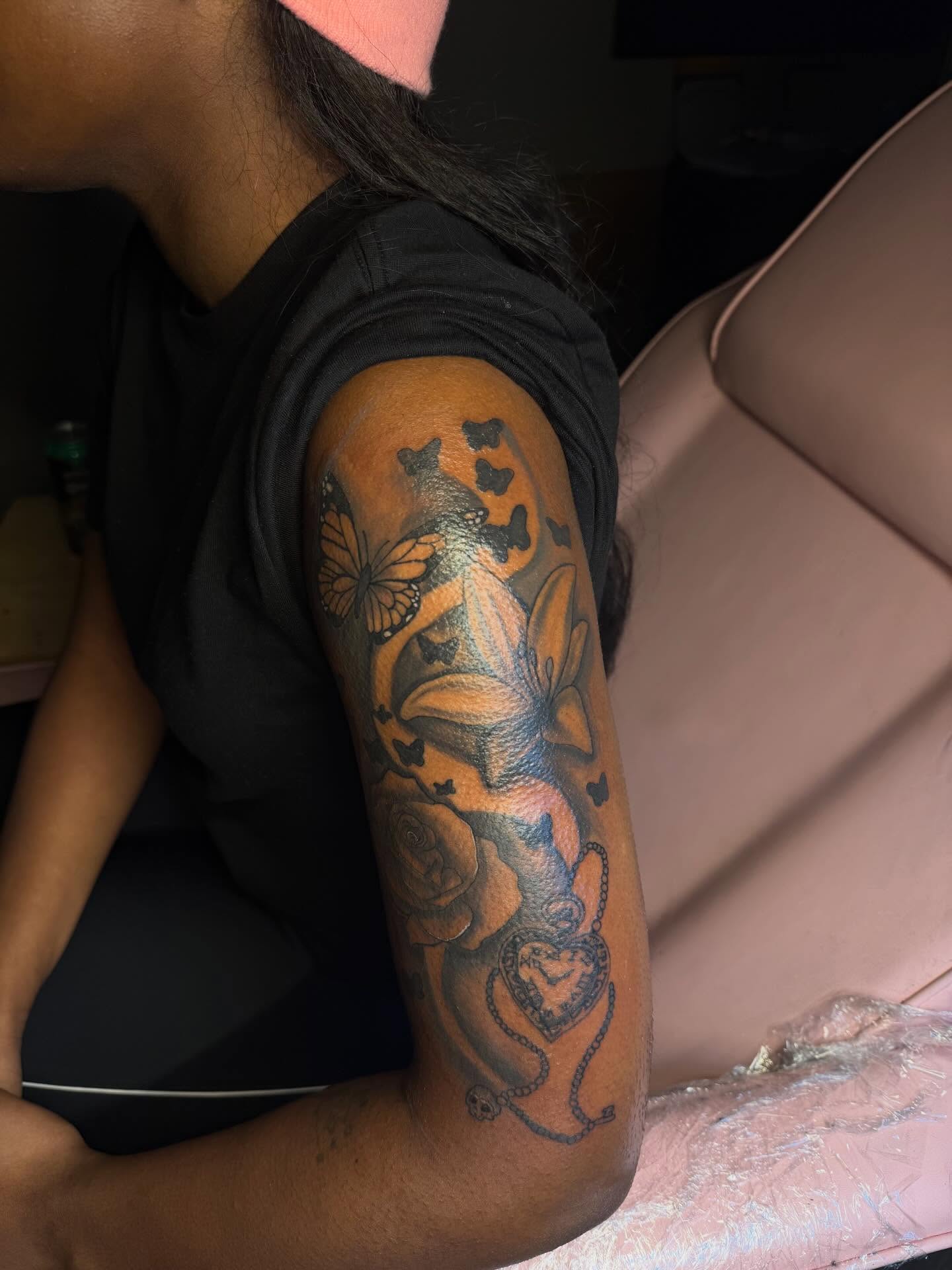 Lilies and butterflies black and grey tattoo on the forearm by Tatted By Layy