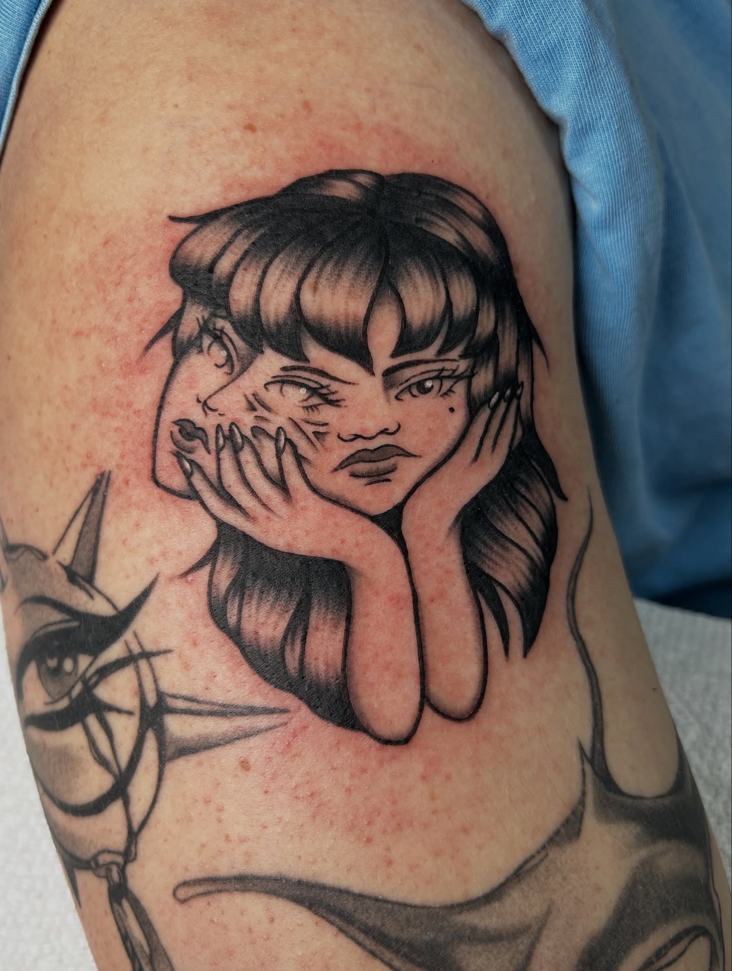 Woman with bangs black and grey tattoo on the upper arm by Dylan James