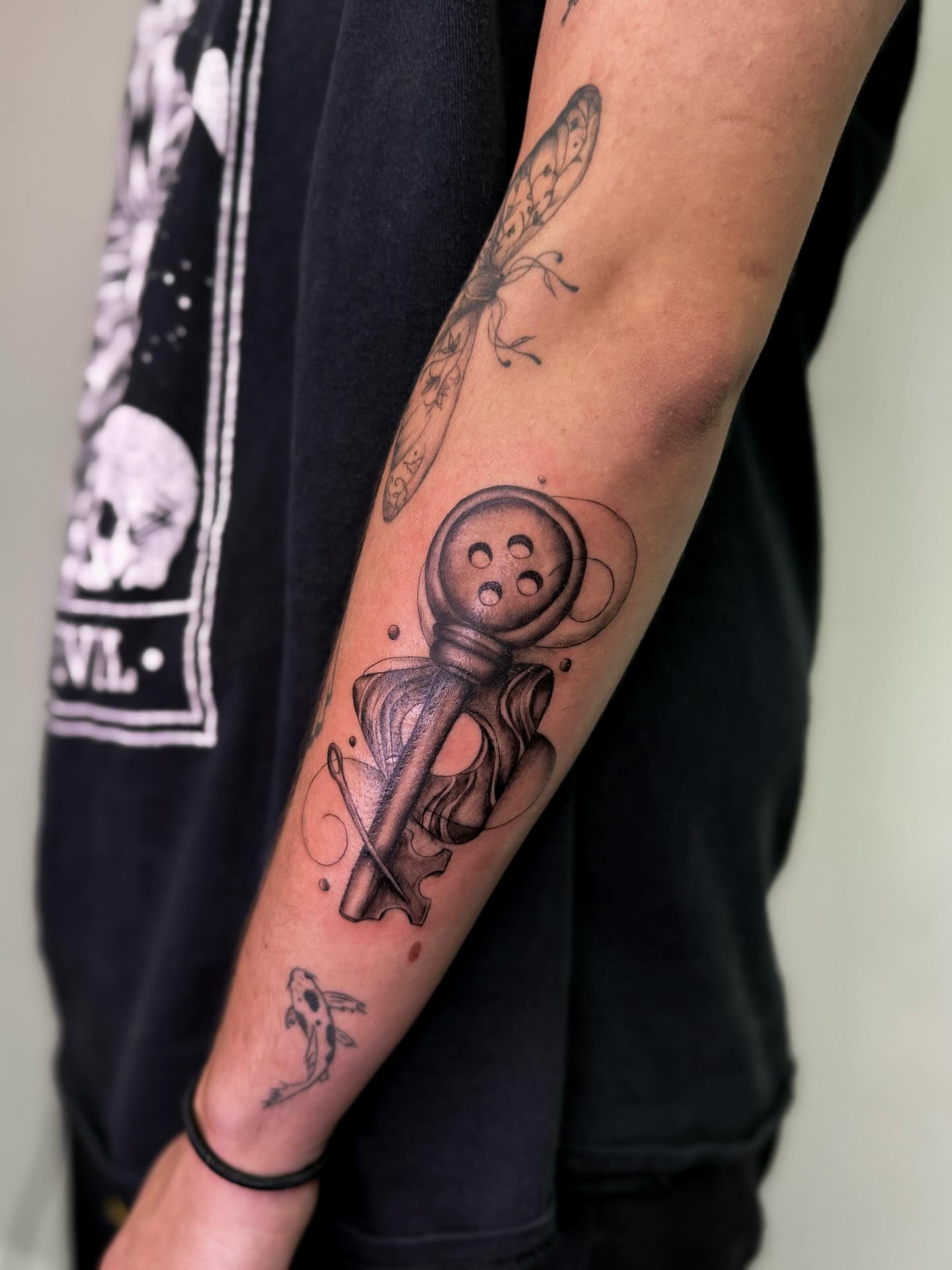 Button and key black and grey tattoo on the forearm by Rachel
