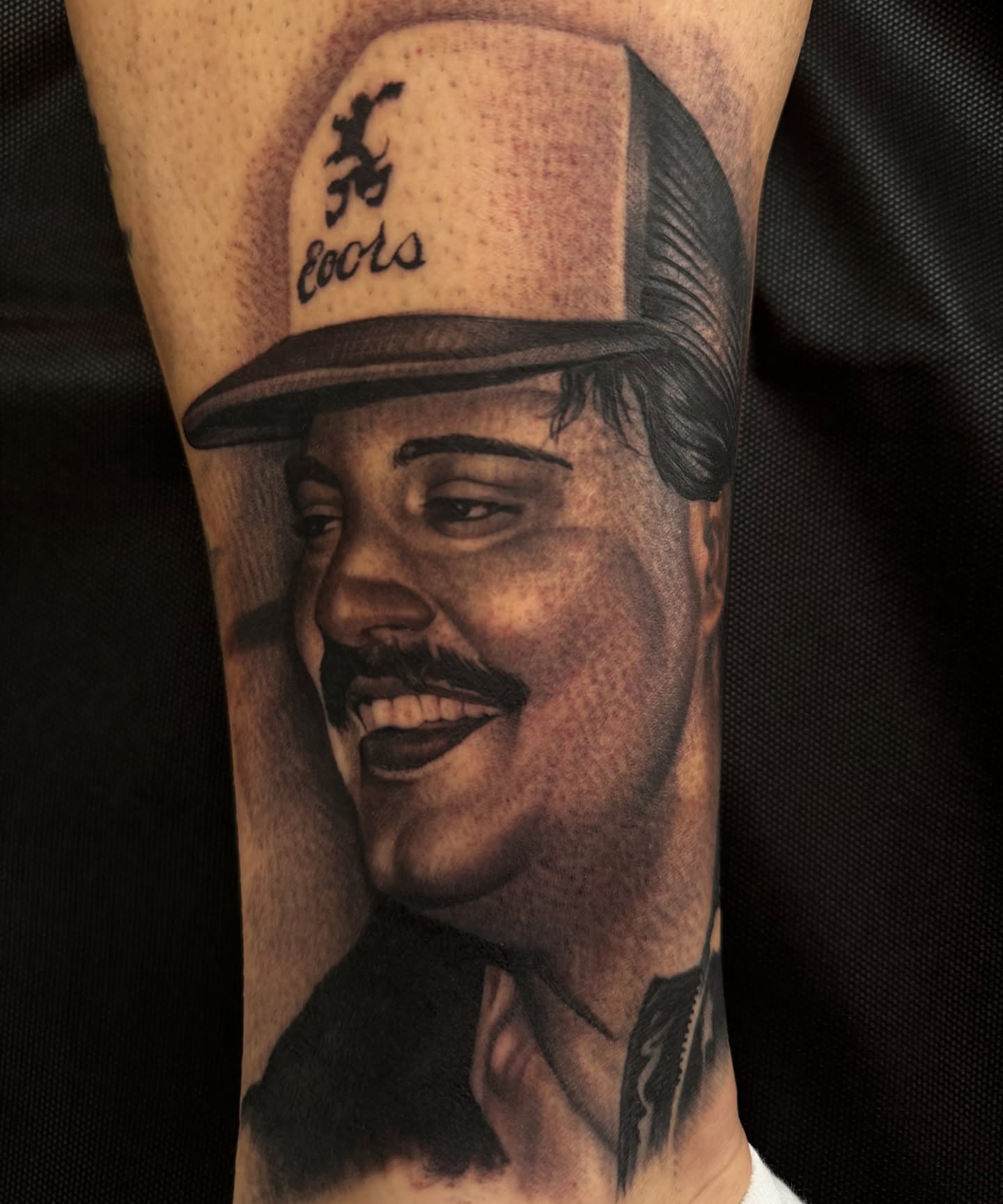 Man wearing Coors hat realism tattoo on the forearm by tombstone
