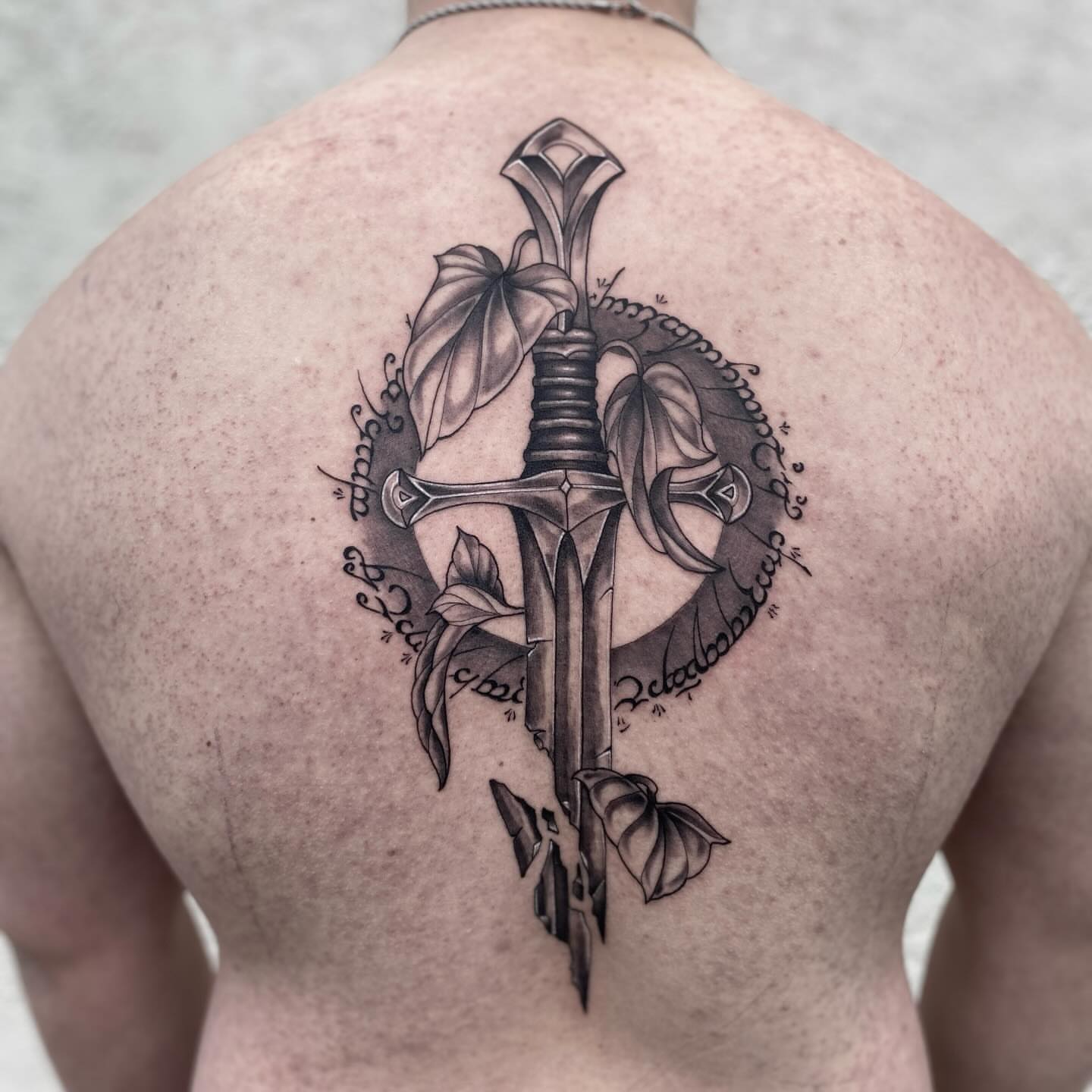 Sword and leaves realism tattoo on the back by Hayden Earley